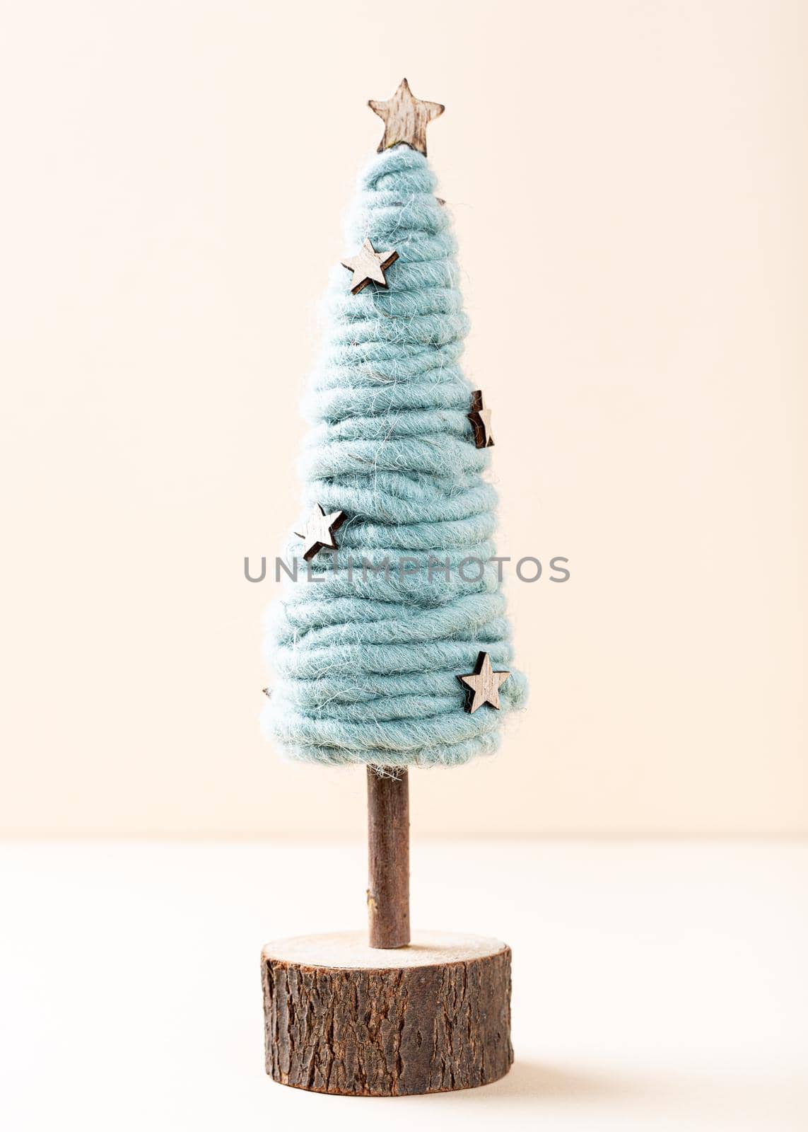 Festive composirion with wooden and felting wool christmas tree over beige background. Copy space, winter holidays greeting card