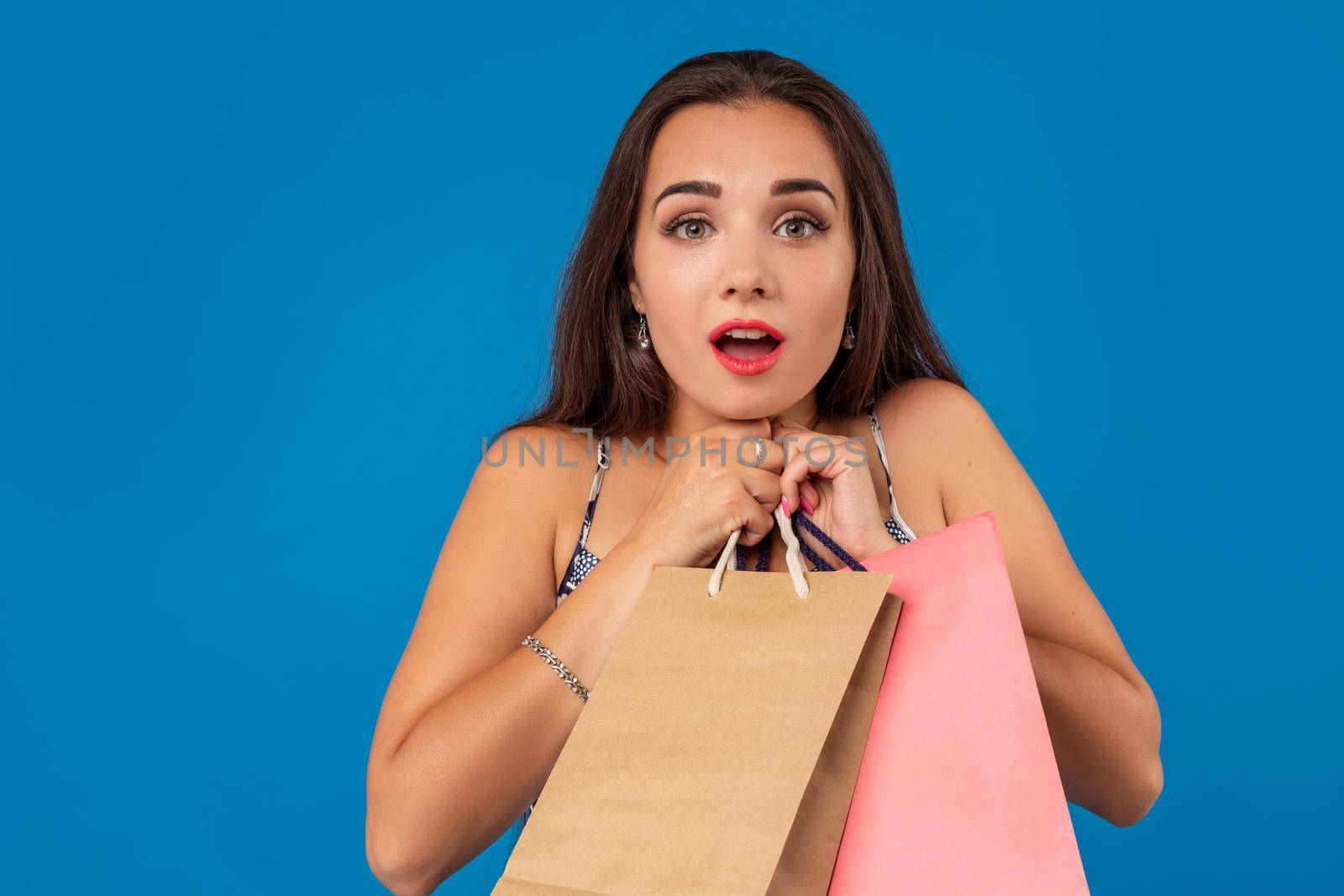 Photo of beautiful young woman with shopping bags on the wonderful blue background. The concept of shopping