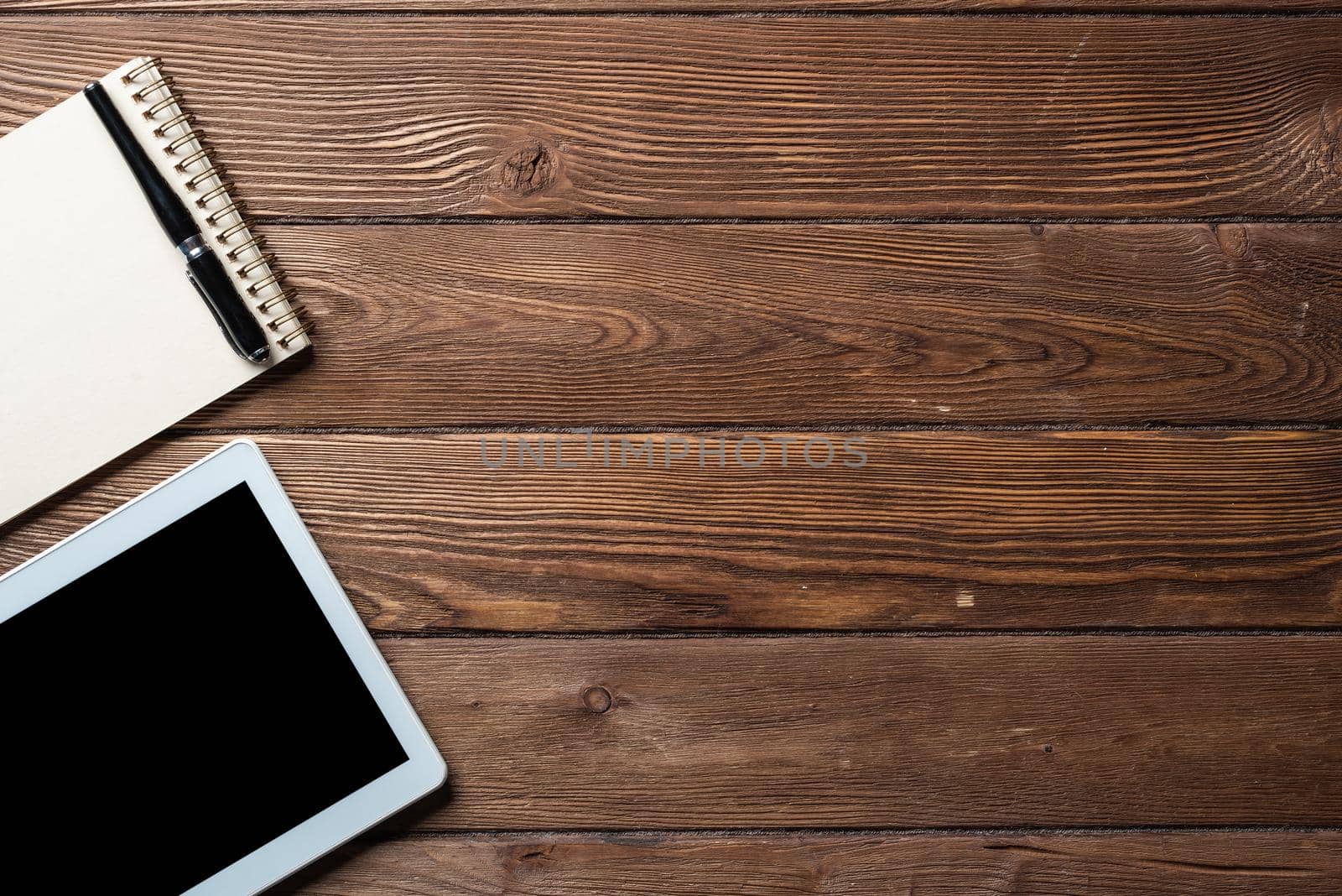 Top view of well organized home office workplace. Spiral notepad, pen and tablet computer on white surface. Education, creativity and working concept. Minimalist business design with copy space.