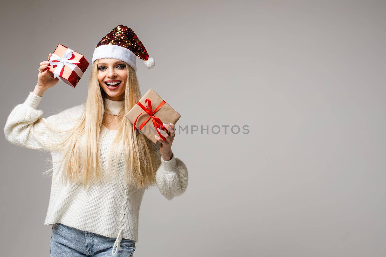 portrait of pretty caucasian woman holds two small presents and poses for the camera isolated on white background by StudioLucky