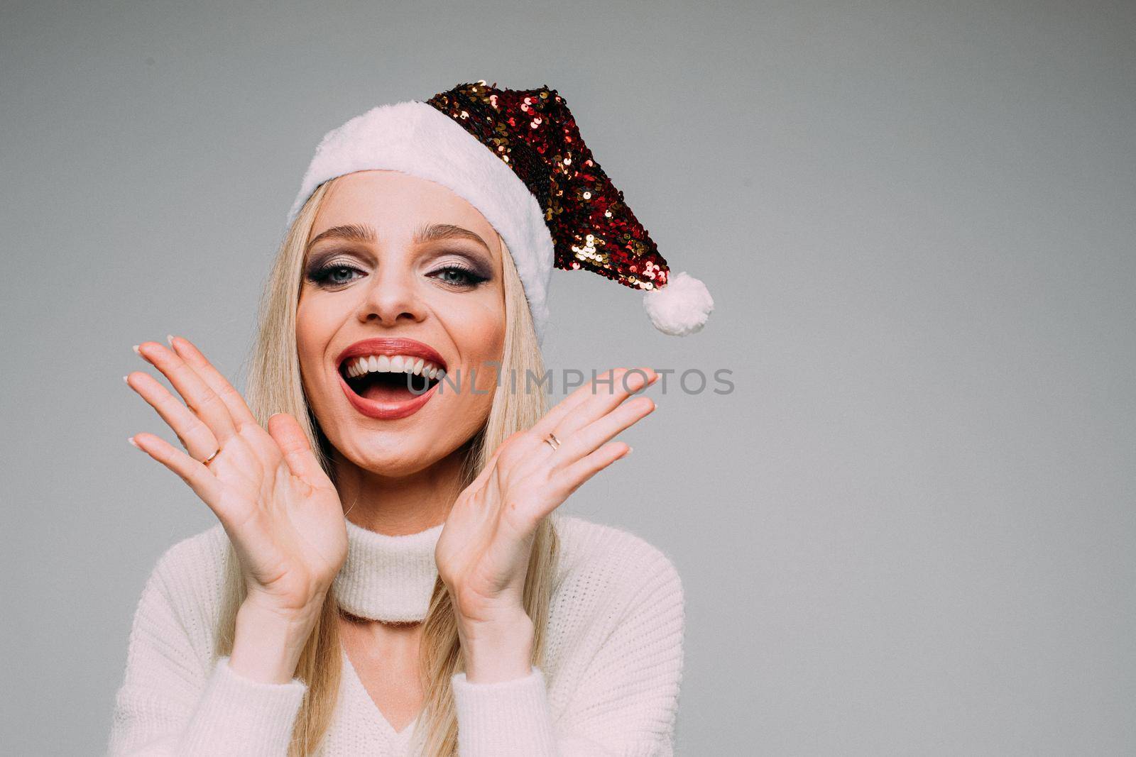 Waist up of happy young woman in red Santa Claus hat celebrating the New Year, isolated on grey background. Copy space