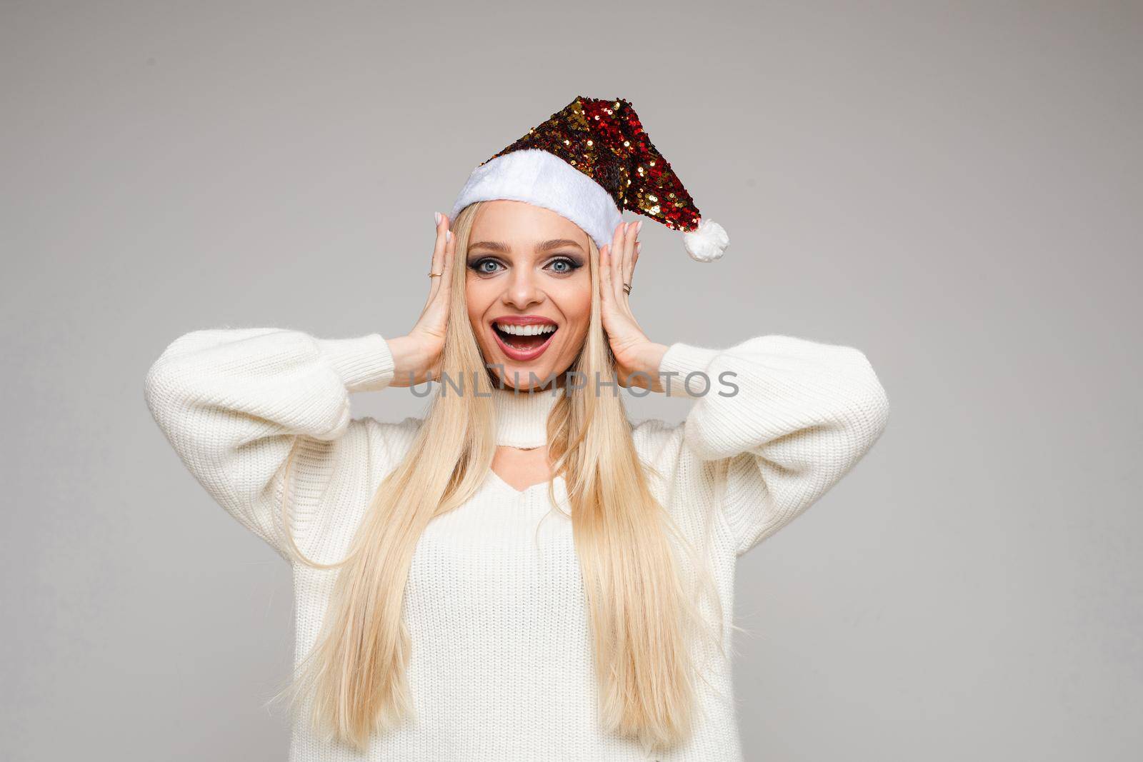 Girl in Santa hat smiling at camera. by StudioLucky