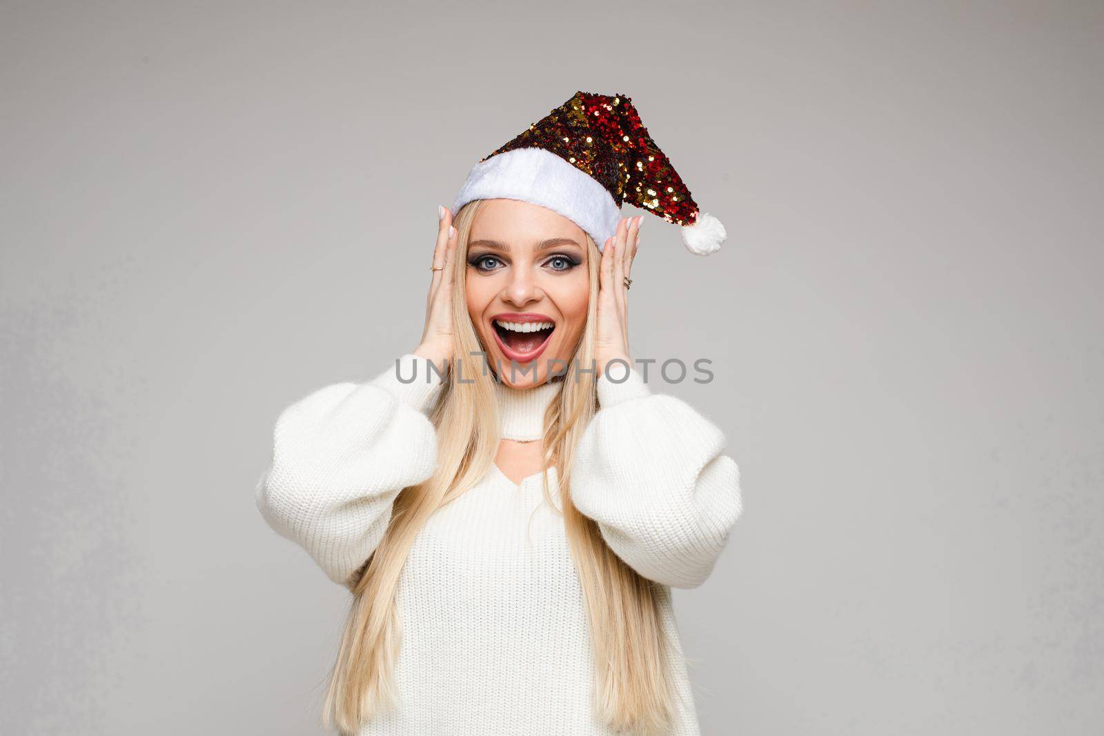 beautiful young woman with blonde hair poses on camera touches her hair and smiles, picture isolated on white backgroung by StudioLucky