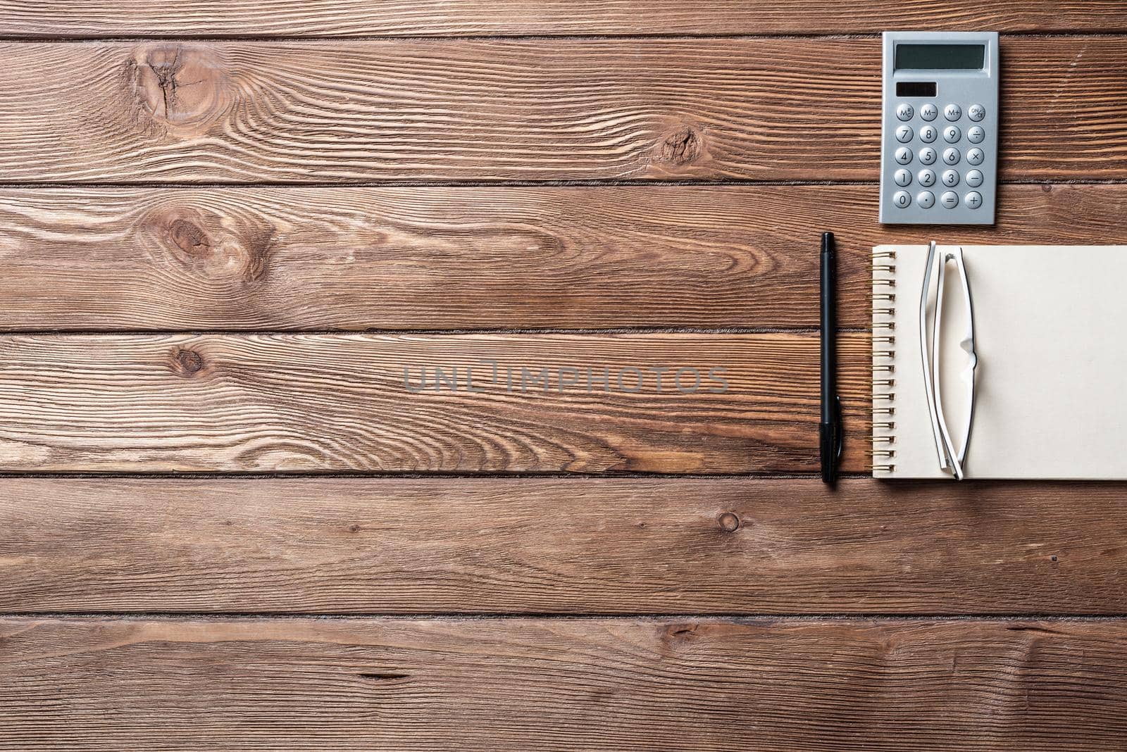 Still life of accountant vintage workspace with office accessories. Flat lay old hardwood desk with notepad, pen and calculator. Accounting and banking services. Finance and investment concept.