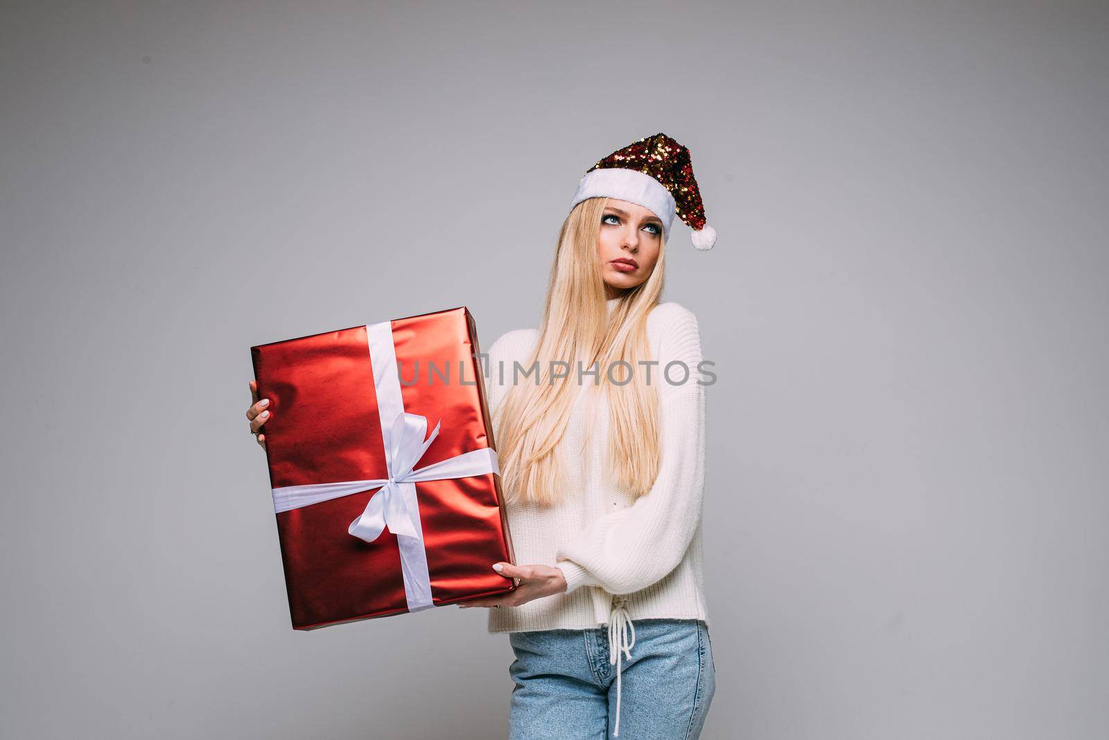 Close-up studio photo of a beautiful young lady in Santa hat cupping hands around mouth and making faces