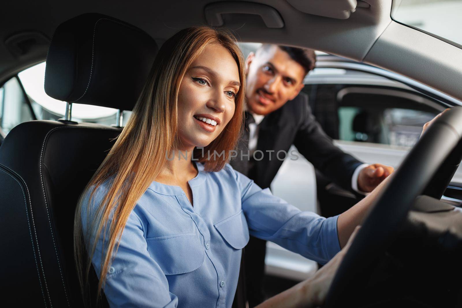 Happy woman new car owner sitting in driver seat by Fabrikasimf