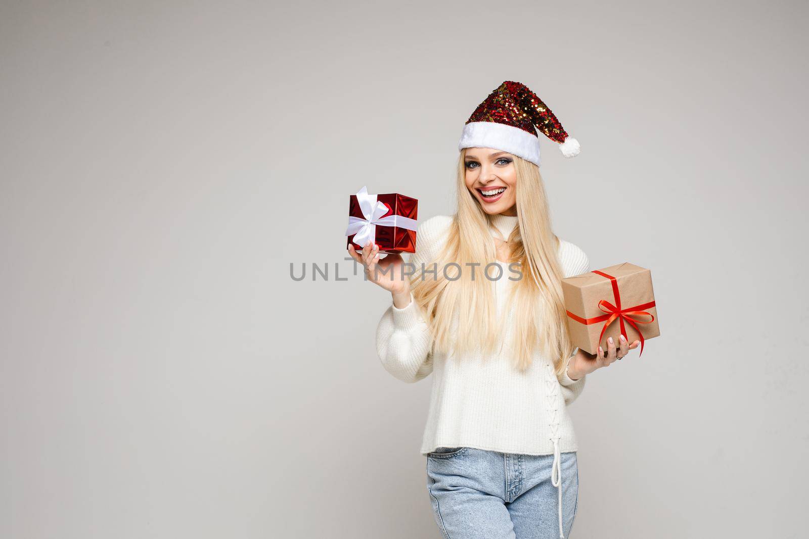 pretty caucasian woman holds two small gifts and smiles isolated on white background by StudioLucky