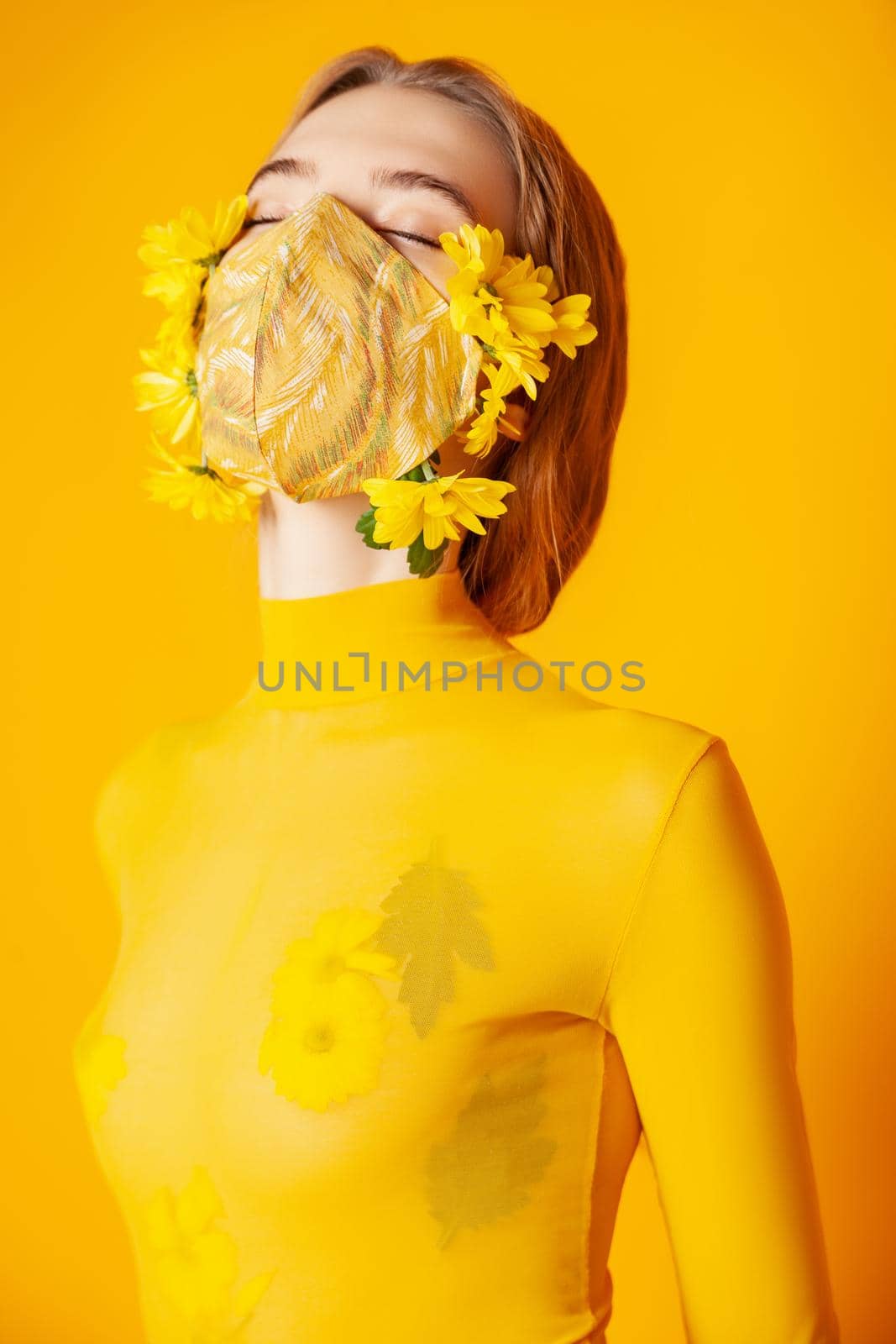 Woman in mask with yellow flowers in studio by Julenochek