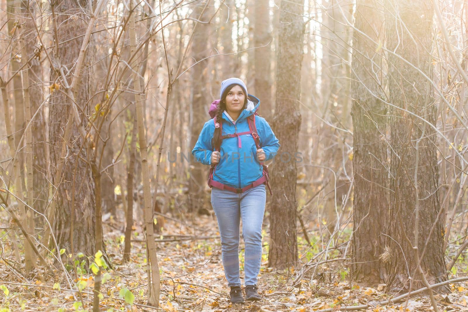 adventure, travel, tourism, hike and people concept - smiling woman walking with backpacks over autumn natural background.