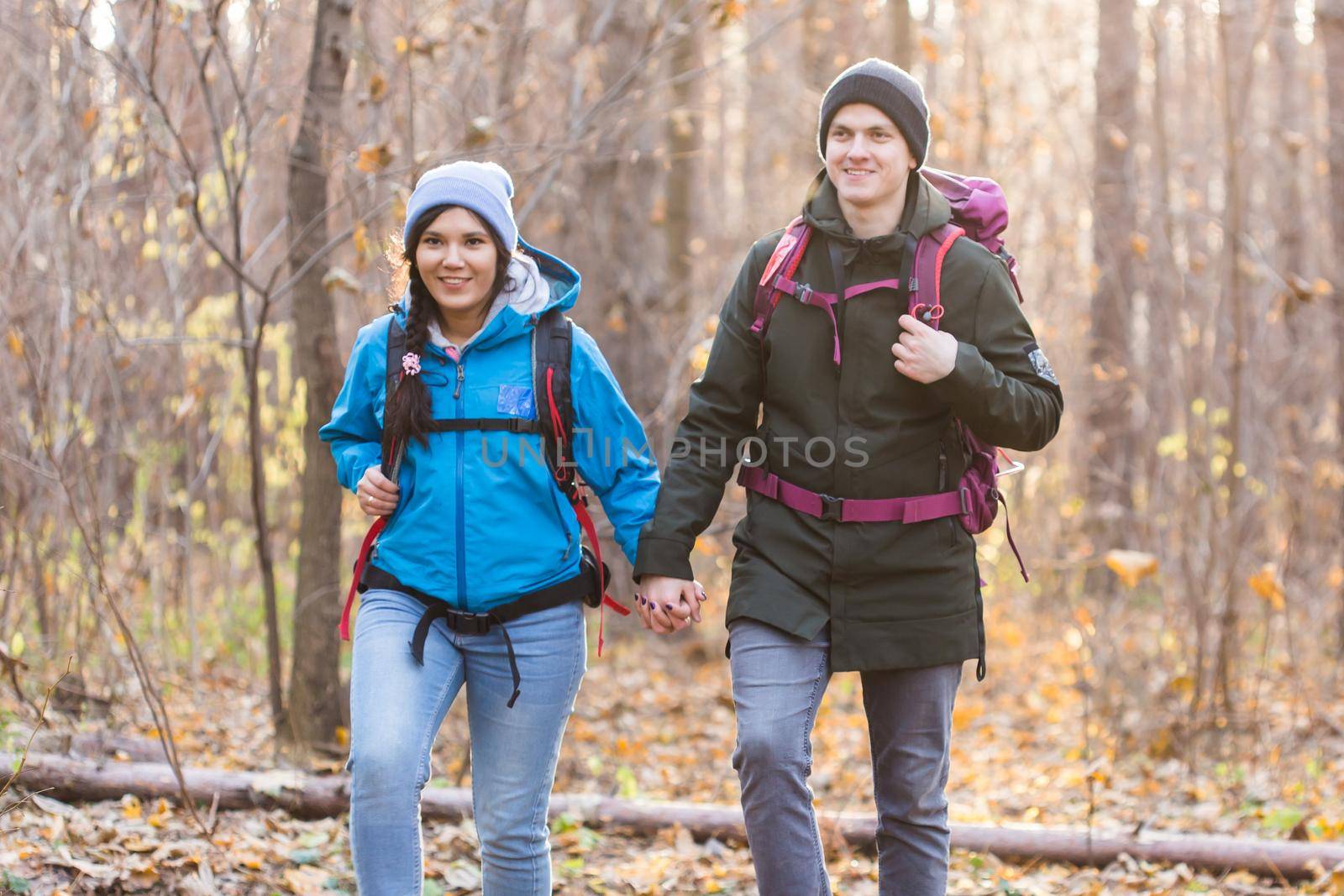 adventure, travel, tourism, hike and people concept - smiling couple walking with backpacks over autumn natural background by Satura86