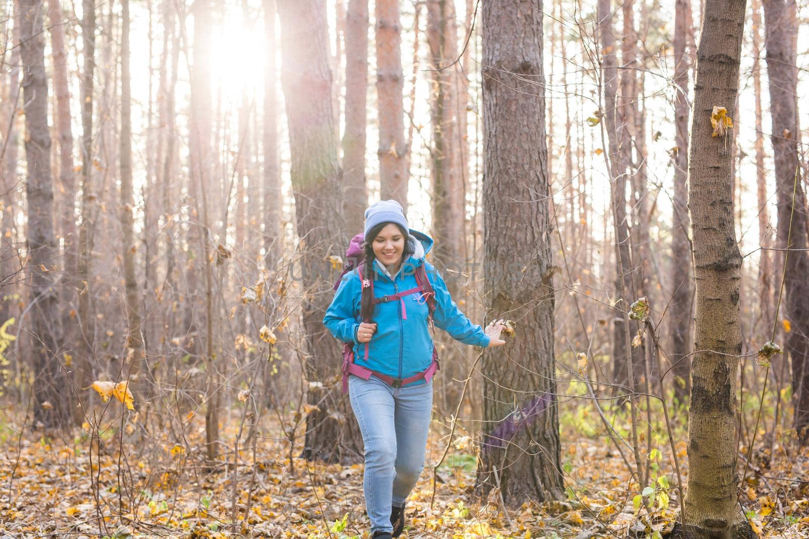 adventure, travel, tourism, hike and people concept - smiling tourist woman walking with backpacks over autumn natural background.