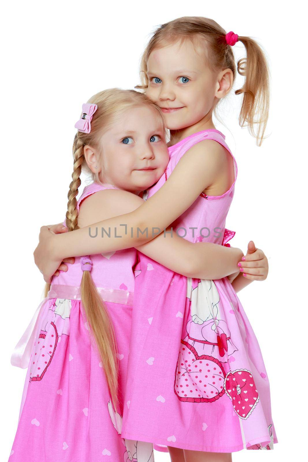 Two cute little girls close-up, in the studio on a white background. The concept of a happy childhood, Beauty and fashion. Isolated.