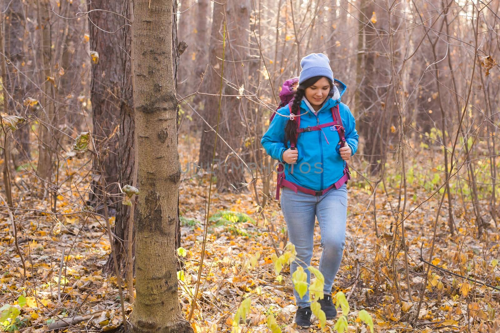 adventure, travel, tourism, hike and people concept - smiling tourist woman walking with backpacks over autumn natural background.