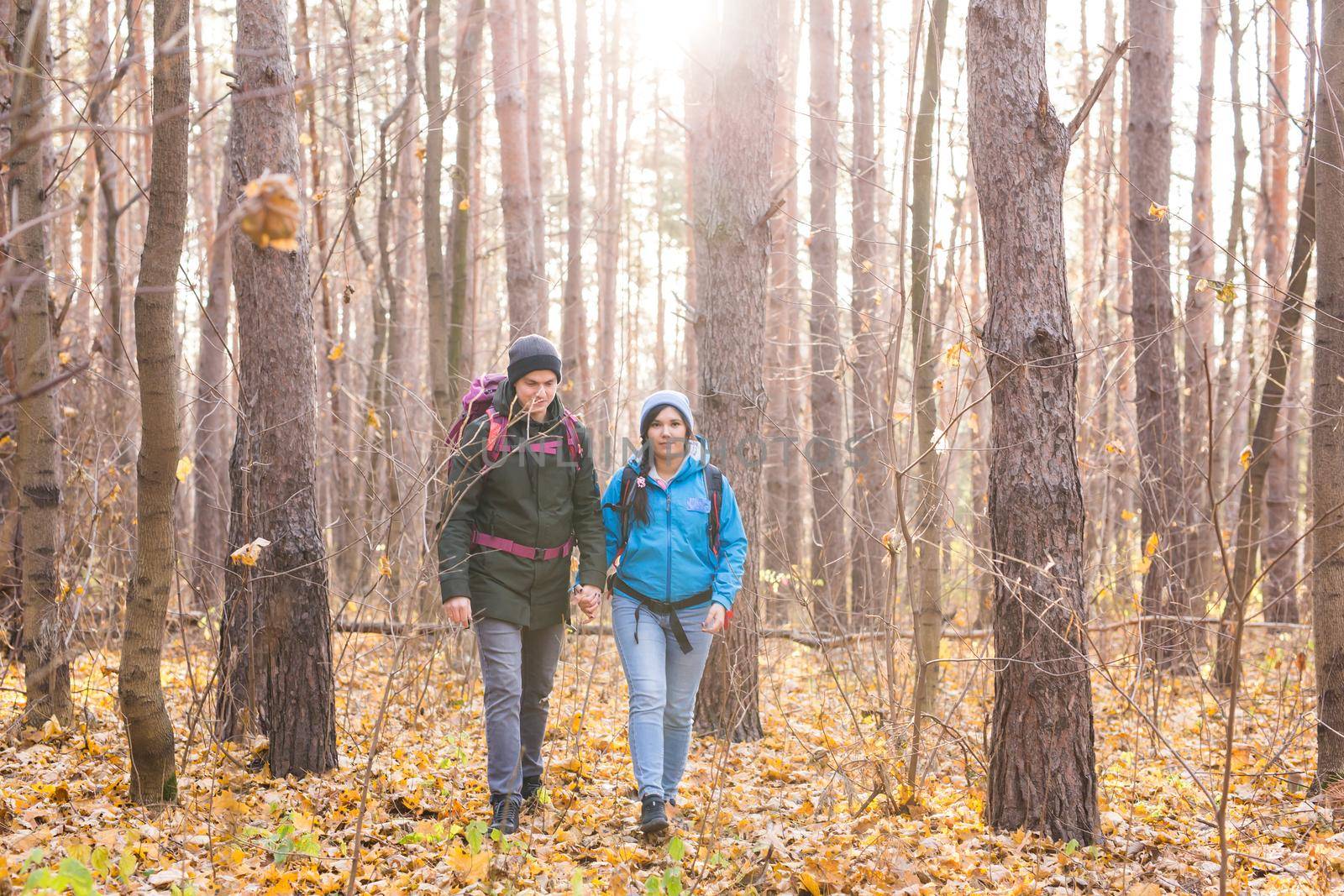 adventure, travel, tourism, hike and people concept - smiling couple walking with backpacks over natural background.