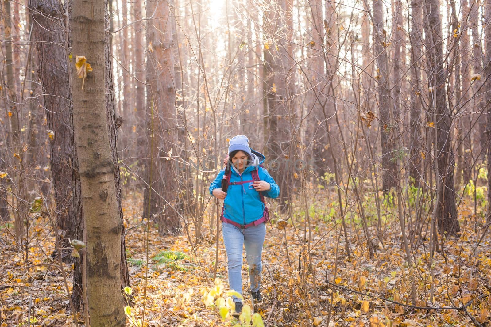 adventure, travel, tourism, hike and people concept - smiling tourist woman walking with backpacks over autumn natural background.