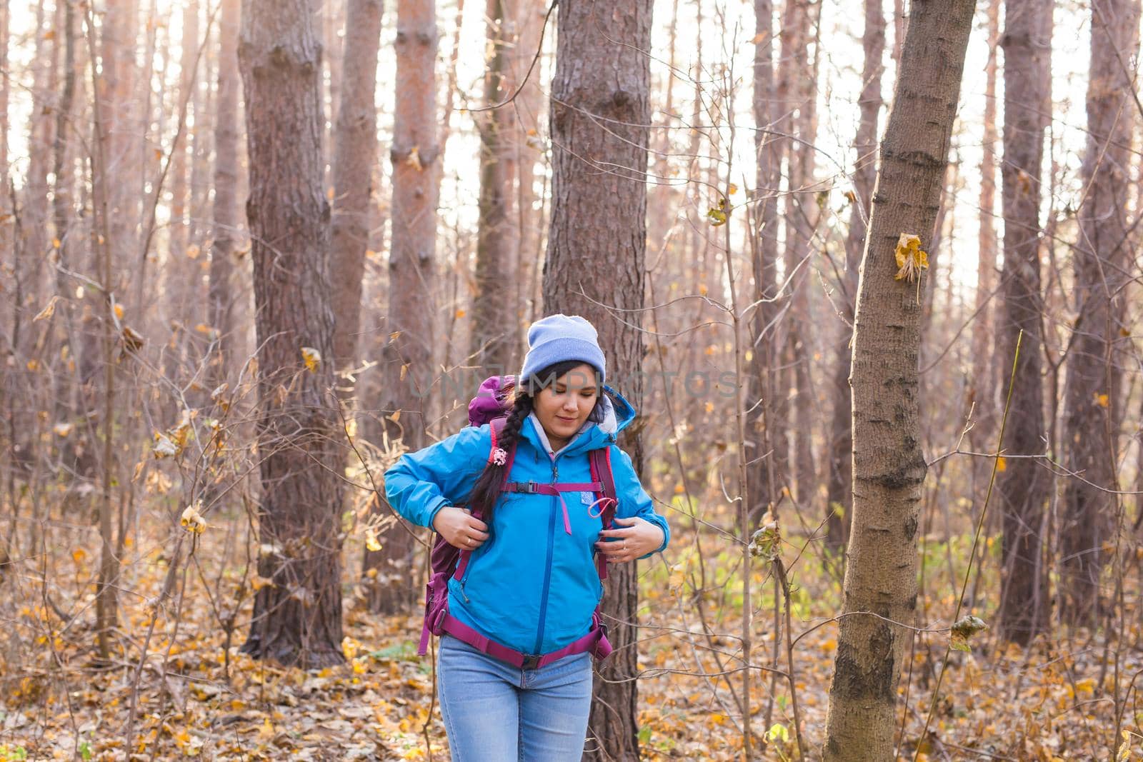 adventure, travel, tourism, hike and people concept - smiling tourist woman walking with backpacks over autumn natural background.