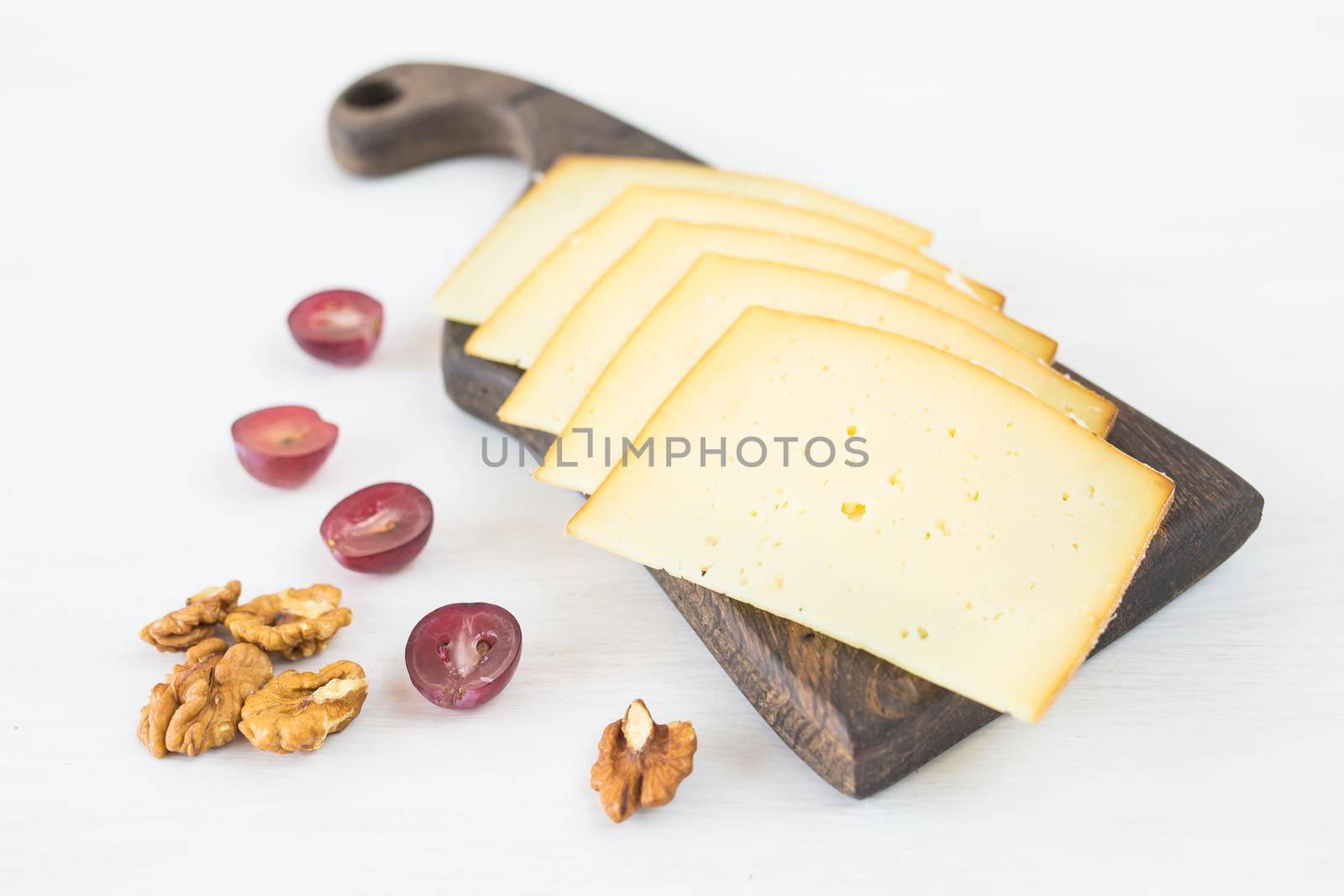 Fresh products. Sliced cheese with grapes and nuts on rustic table. by Satura86