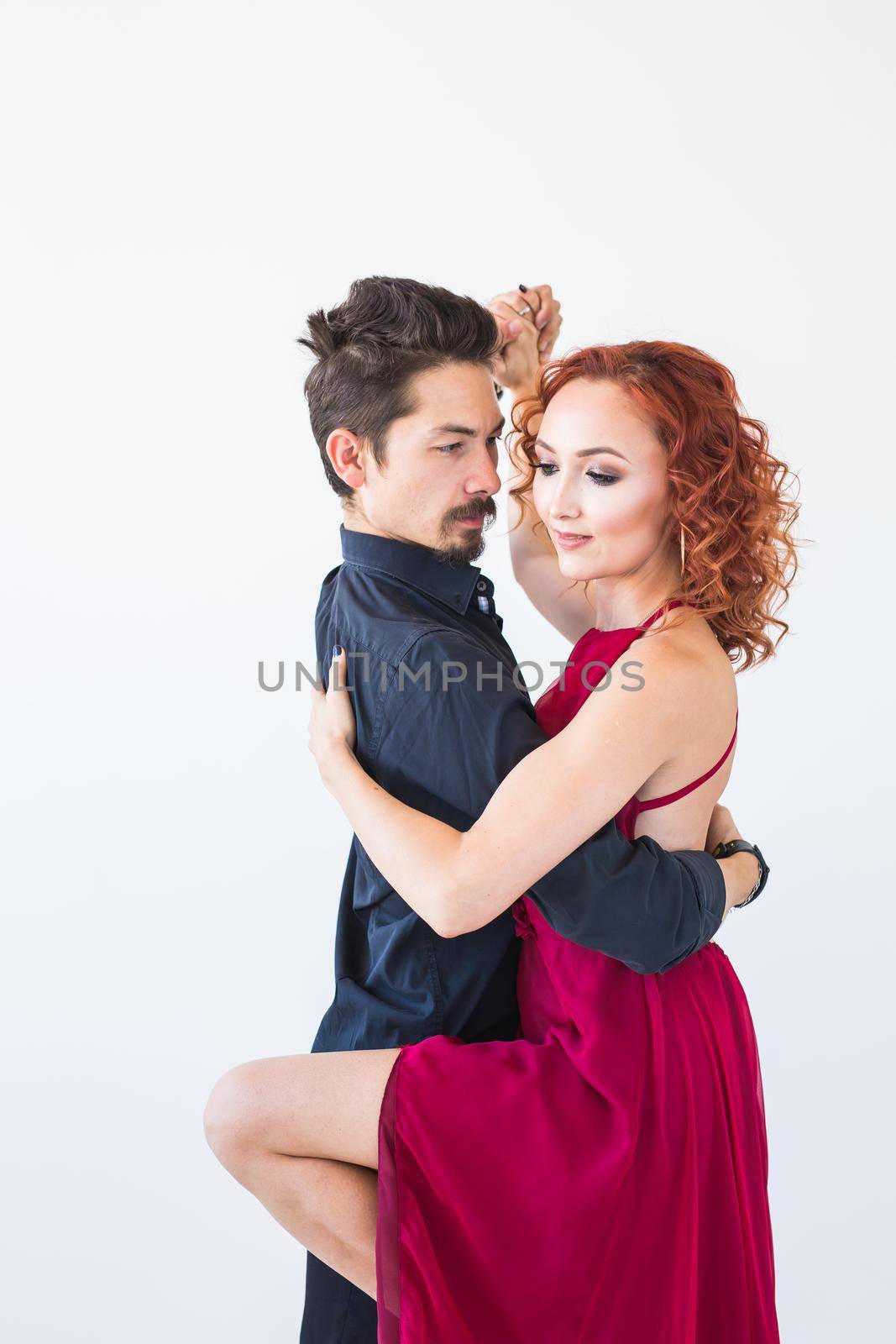 Social dance, bachata, kizomba, salsa, tango concept - Woman dressed in red dress and man in a black costume over white background by Satura86