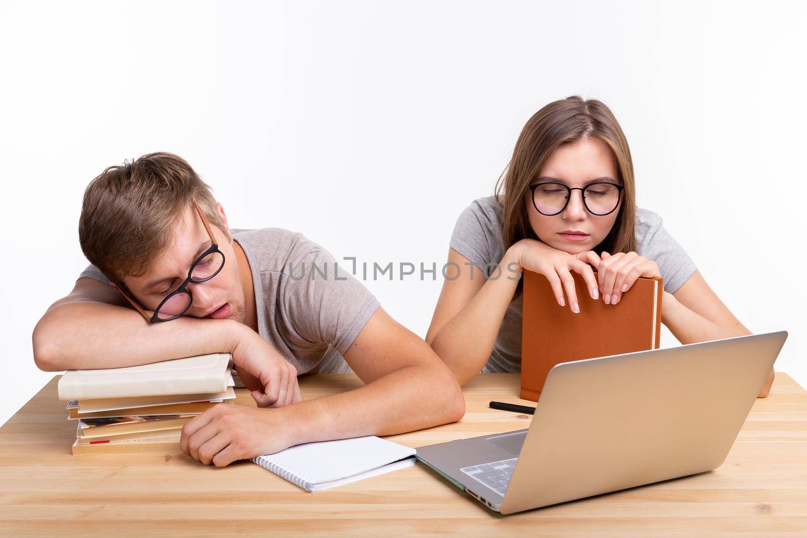 Education, people concept- a couple of young people in glasses look like they are bored of learning homework.