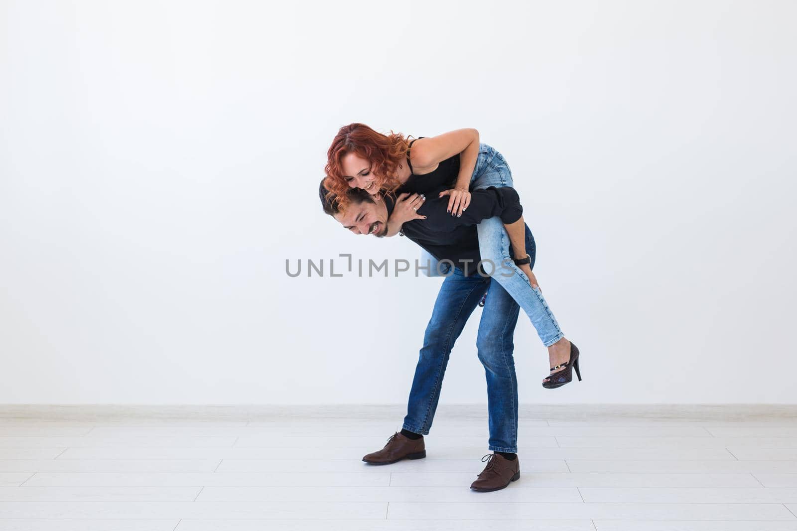 Friendship, people concept - young woman jumped on the man's back.