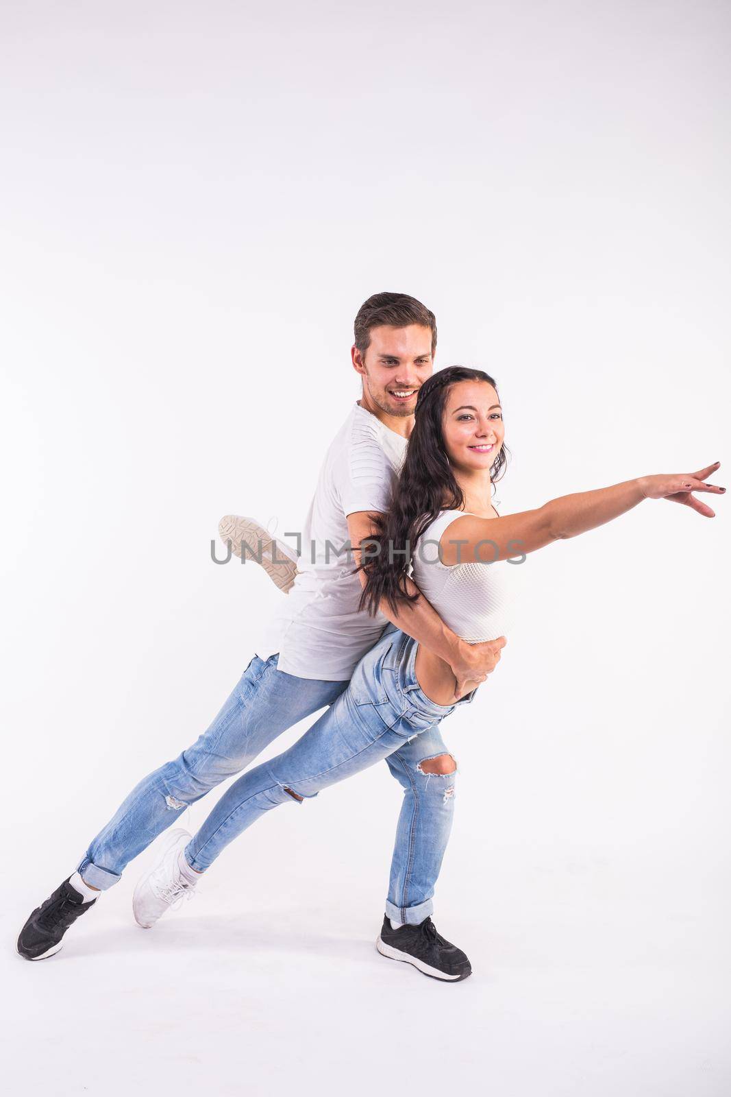 Young couple dancing social dance bachata, merengue, salsa, kizomba. Two elegance pose on white room. by Satura86