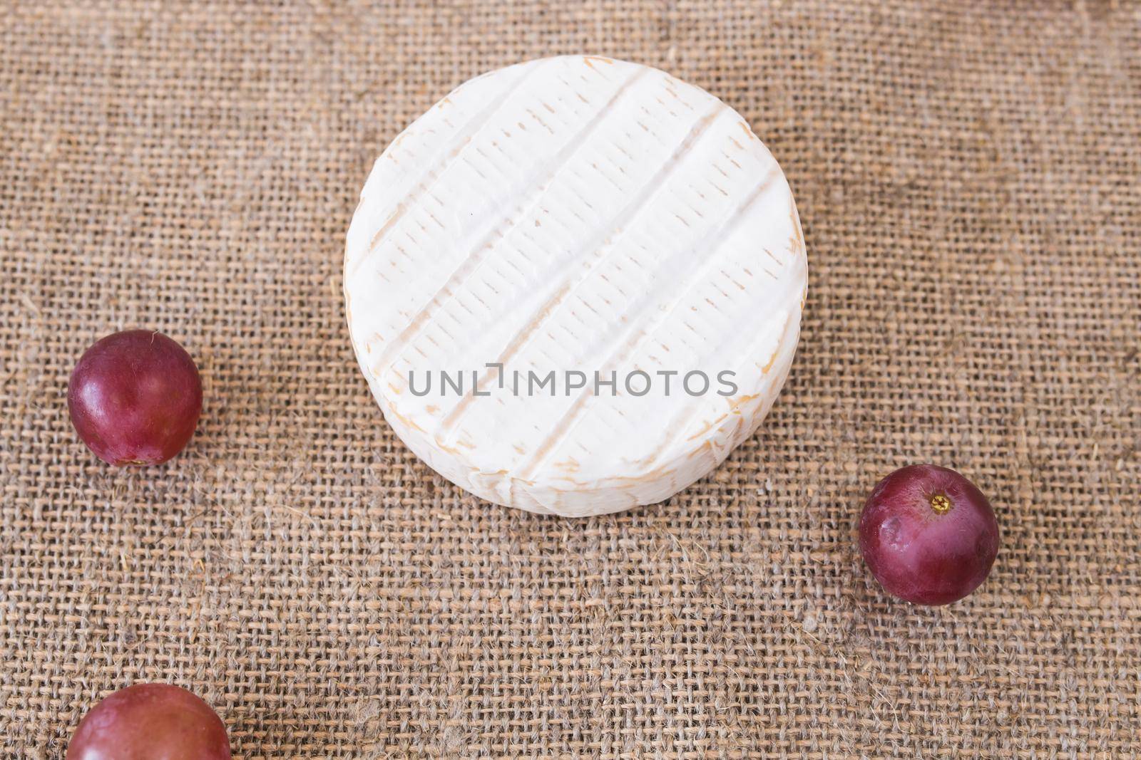 Brie or camembert cheese with grapes on rustic background.