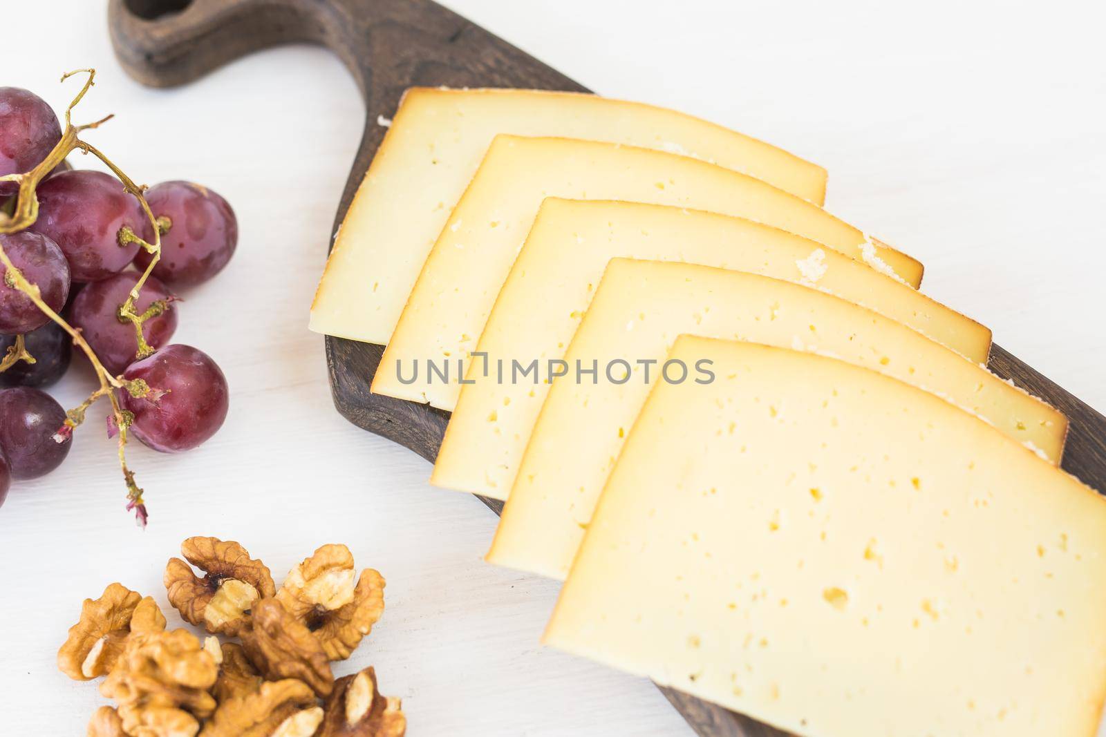 Fresh products. Sliced cheese with grapes and nuts on rustic table. by Satura86