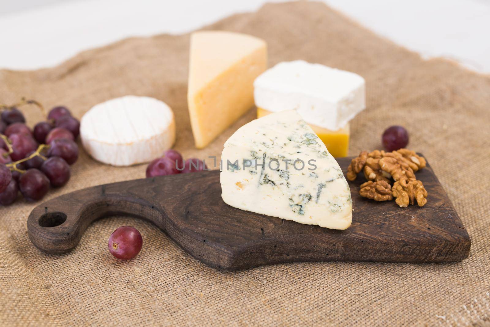 Various types of cheese, blue cheese and brie with grapes and nuts.