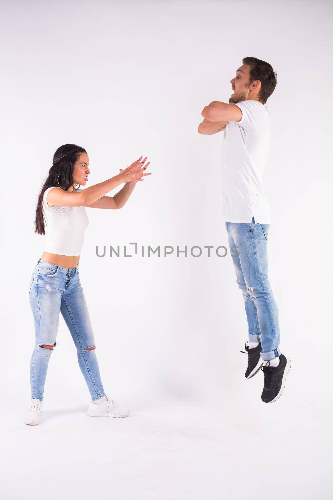 Psychological manipulation, relationship problems and female dominance concept - Young couple fighting. Woman controls a man in the distance by Satura86