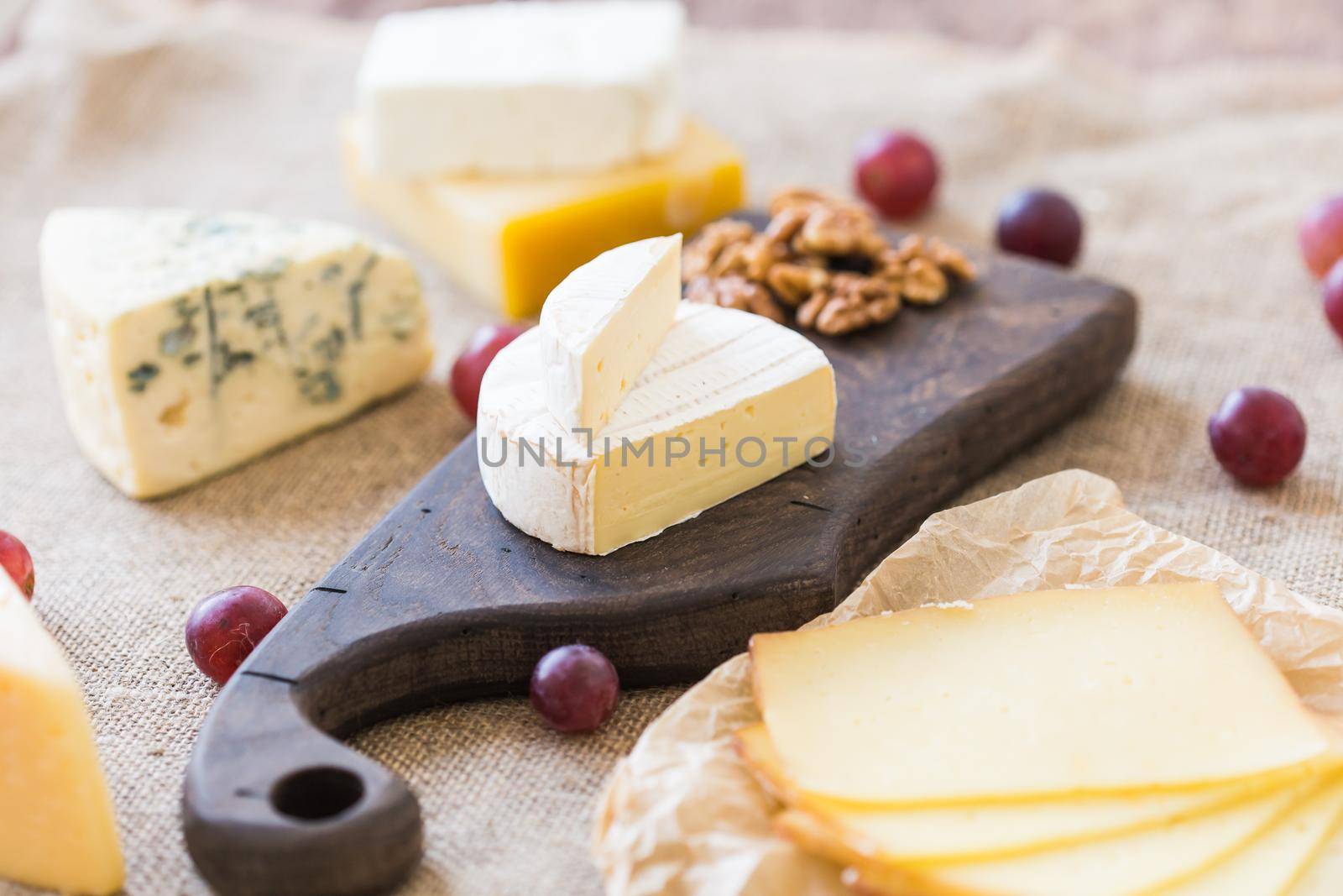 Fresh products. Cheese, brie, Camembert, grapes and nuts on rustic table. by Satura86