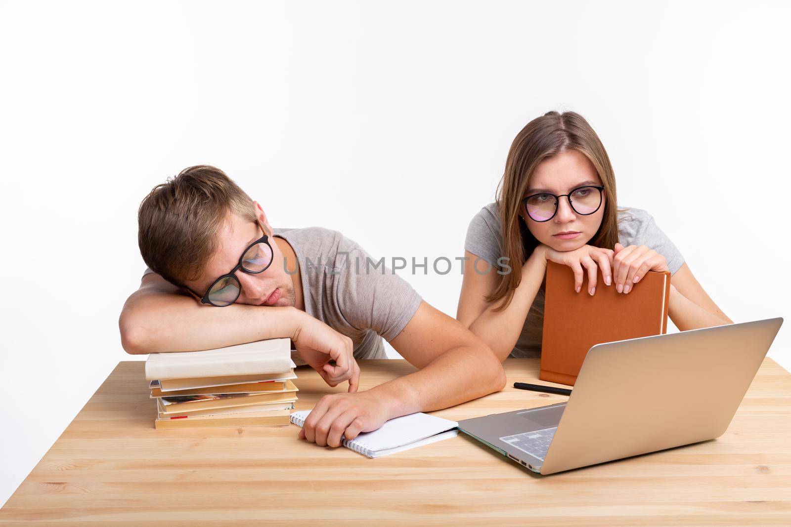 Education, people concept- a couple of young people in glasses look like they are bored of learning homework.