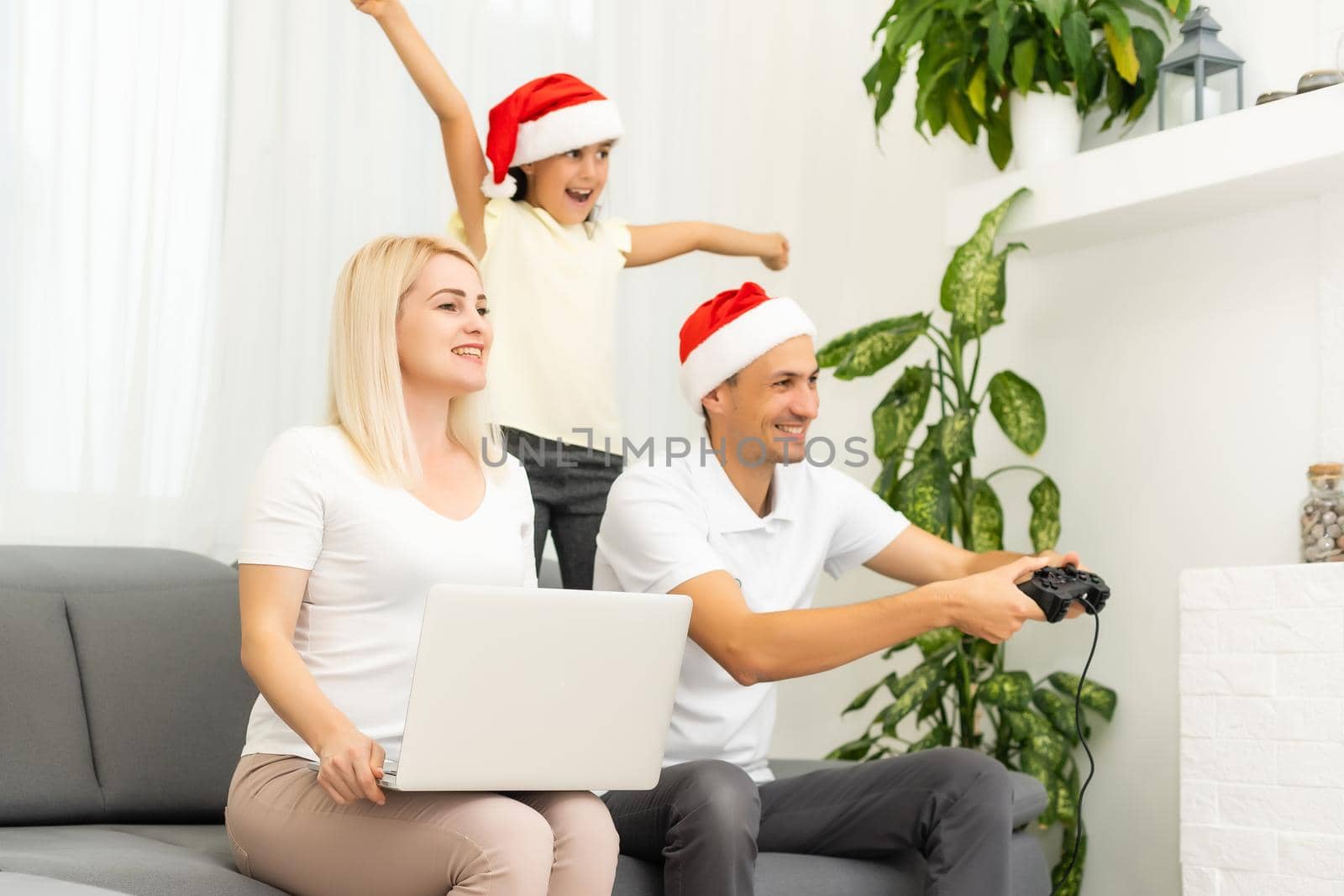 Happy family sitting on a sofa and playing video games. Christmas