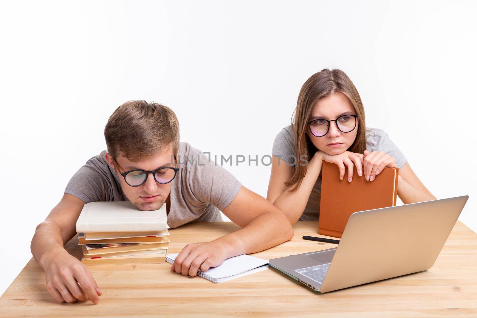 Education, people concept- a couple of young people in glasses look like they are bored of learning homework.