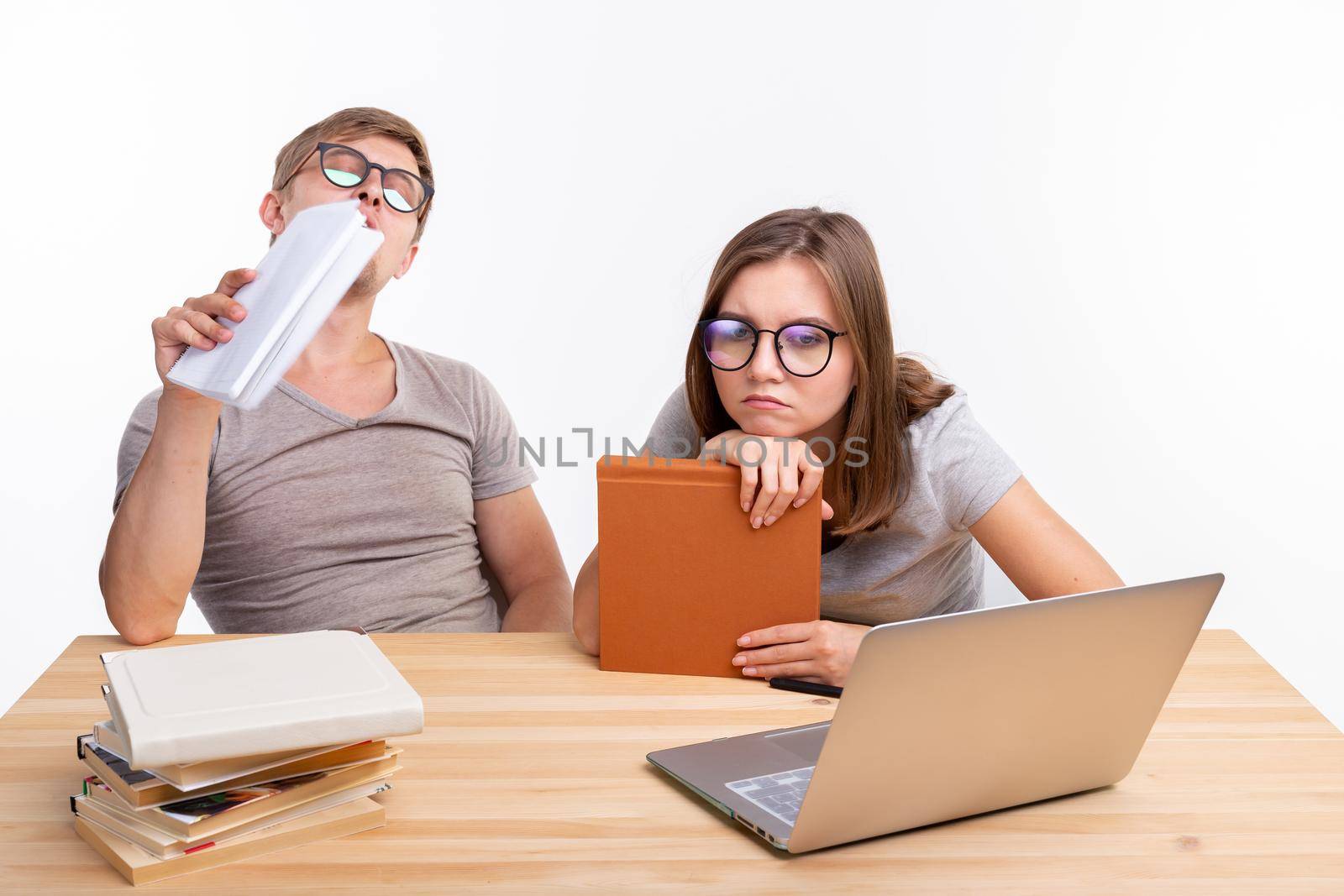 Education and people concept- a couple of young people in glasses look like they are bored of learning homework by Satura86