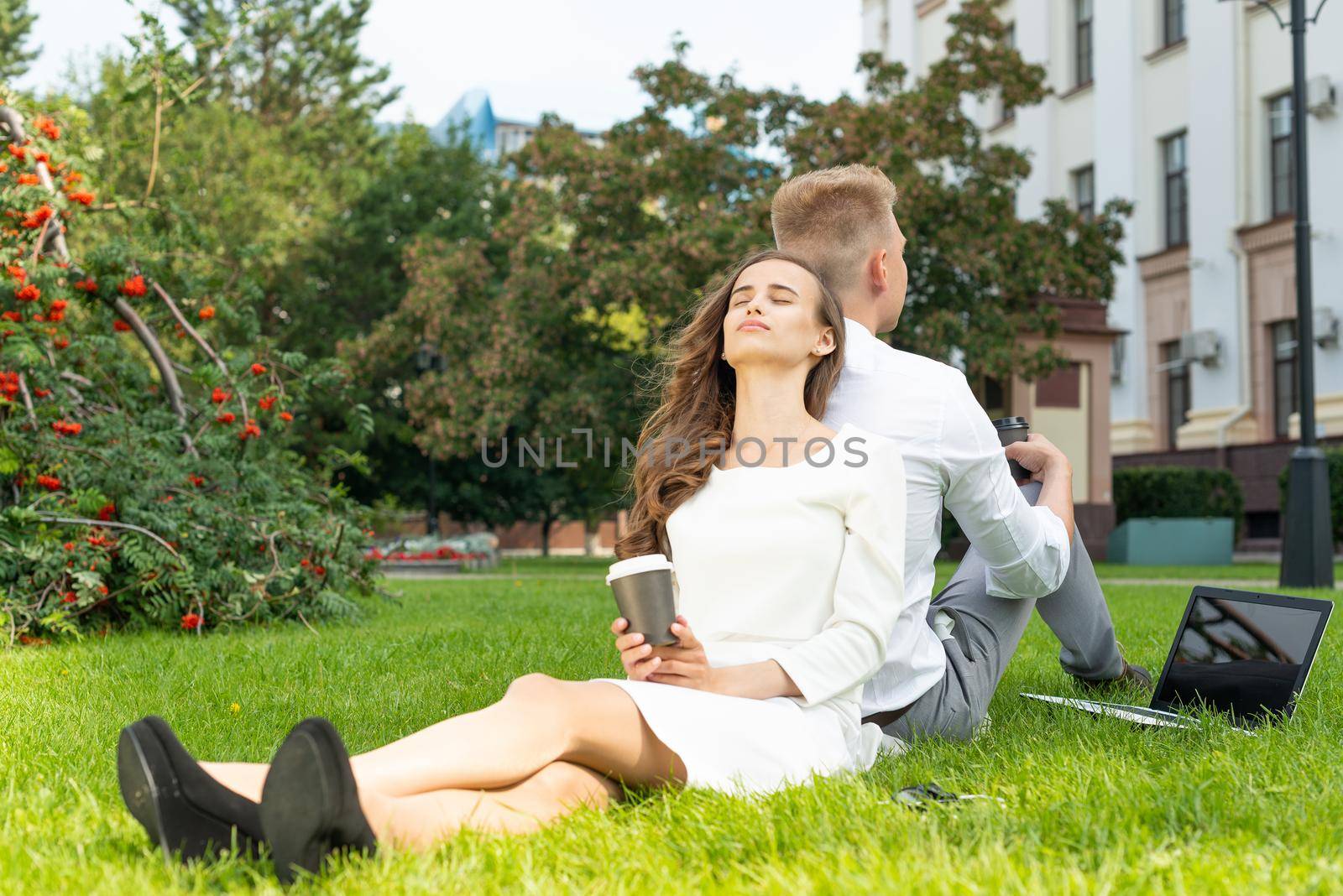 Business persons in the park sit on the grass in the park