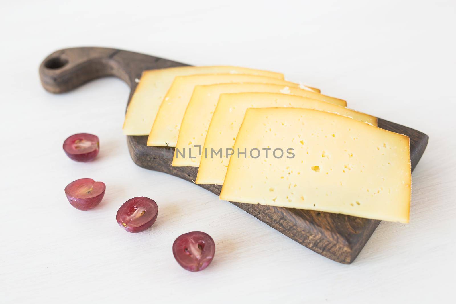 Fresh products. Sliced cheese with grapes on rustic table. by Satura86