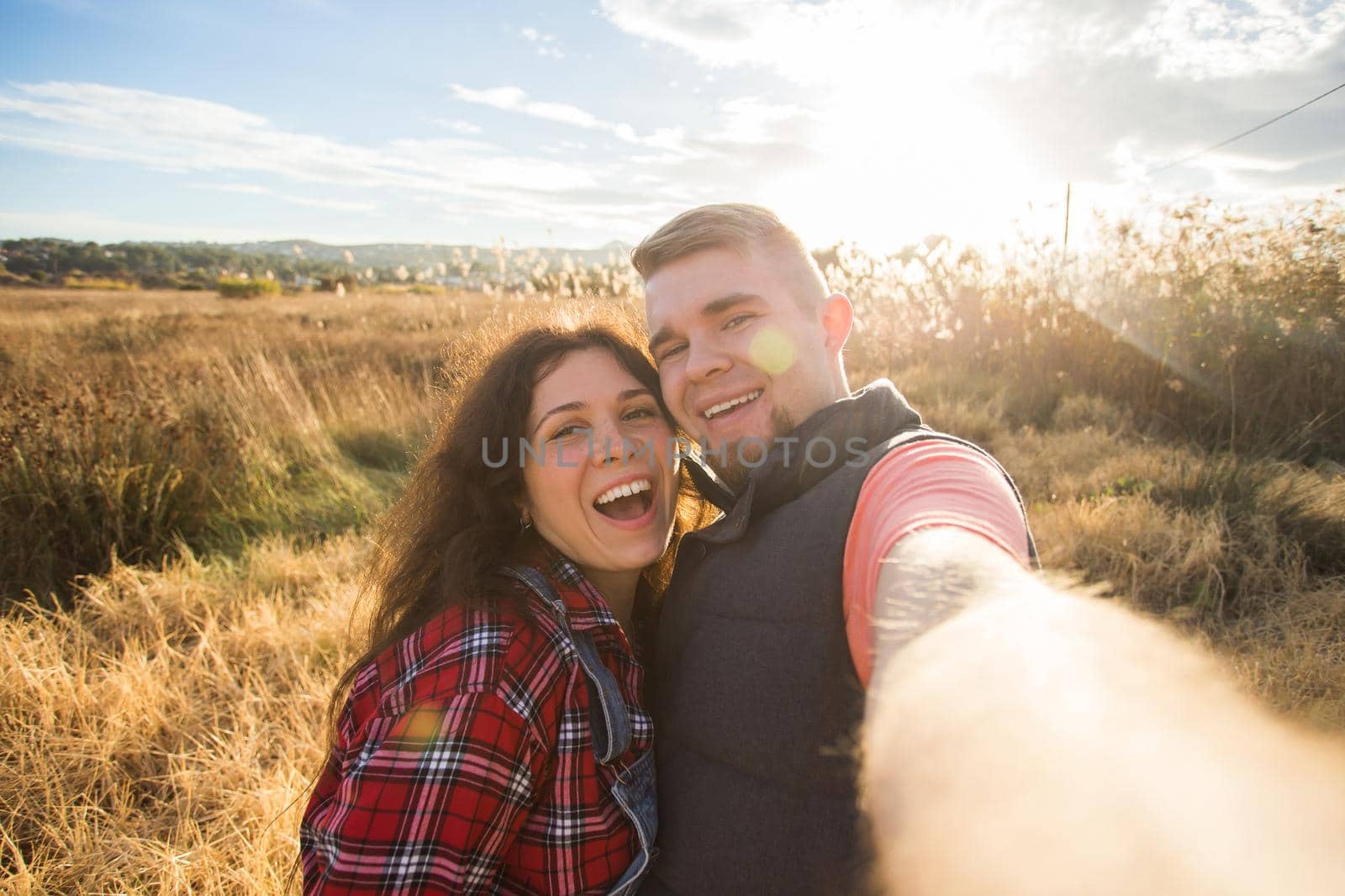 Travel, holidays and nature concept - Happy couple taking a selfie at a field.
