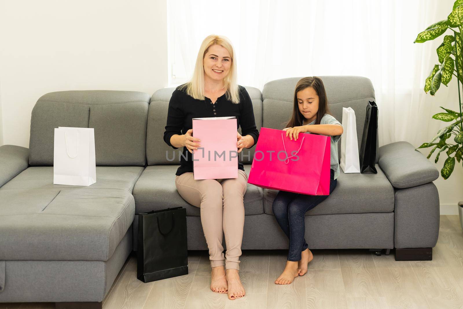 holidays, presents, christmas, x-mas, birthday concept - happy mother and child girl with gift bags