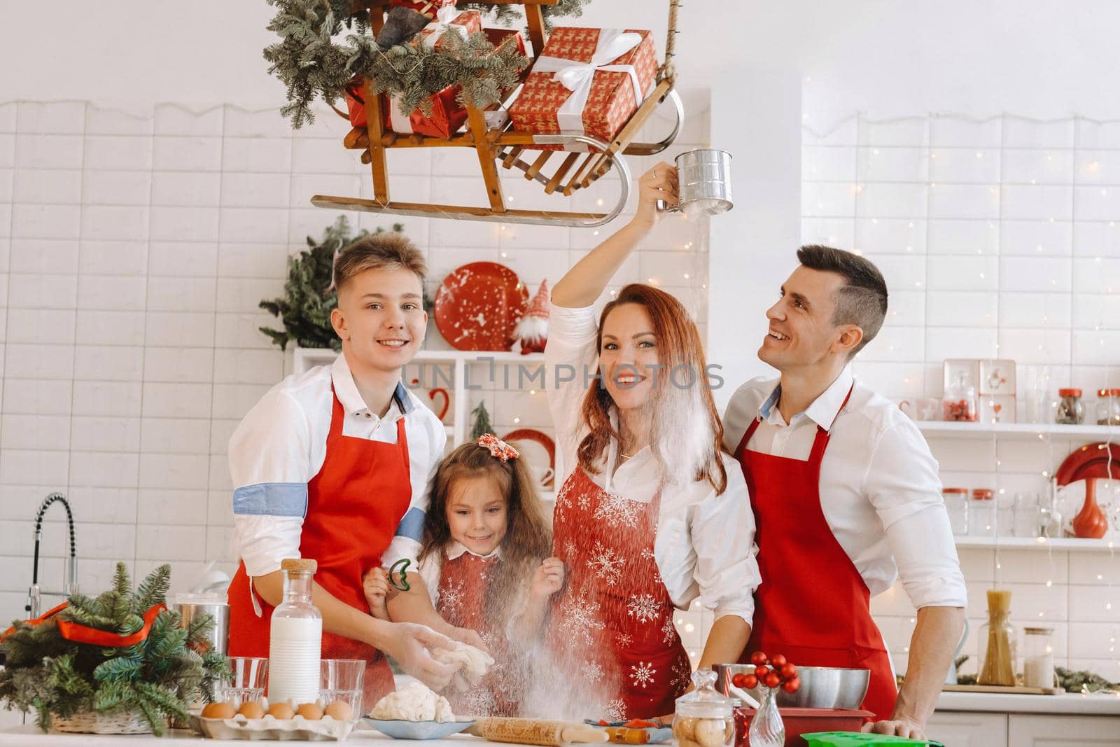 A happy family is standing in the Christmas kitchen and preparing dough for making cookies.