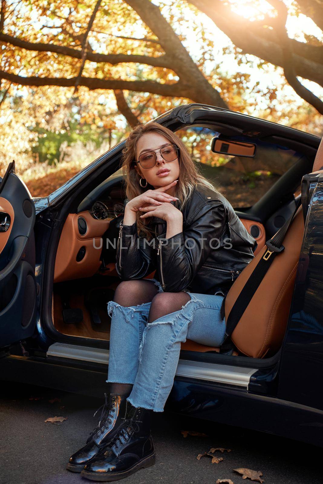 Sexy young woman in jeans is sad in a cabriolet by friendsstock