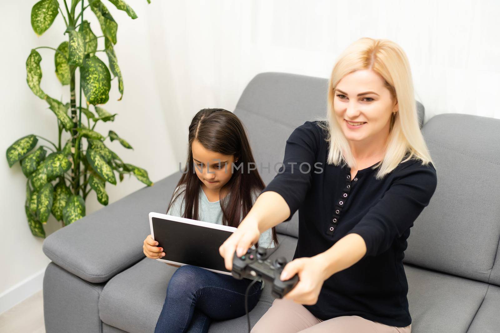 Mother and daughter sittingr in a playroom, playing video games and having fun.