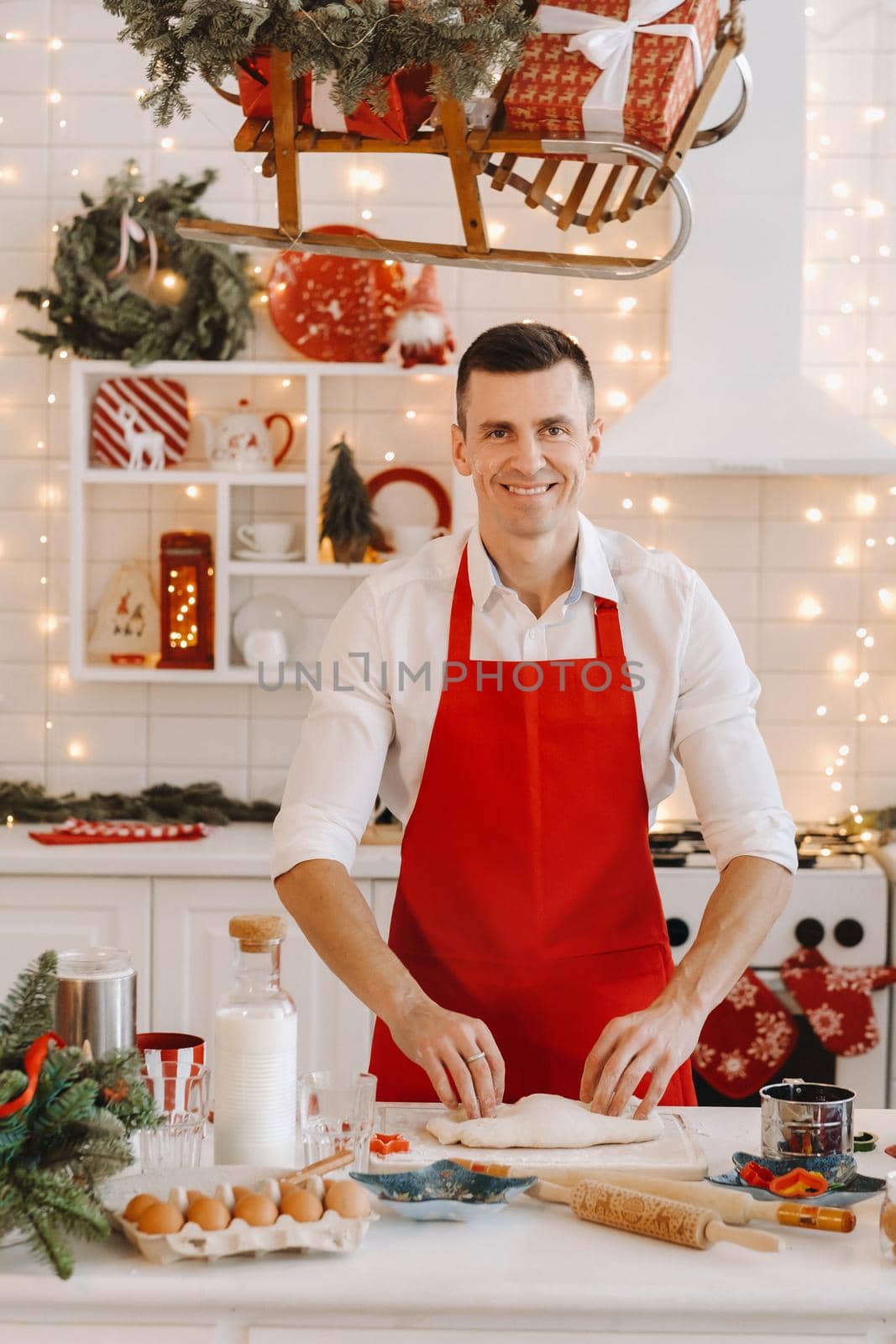 A male chef prepares dough in the Christmas kitchen before the New year by Lobachad