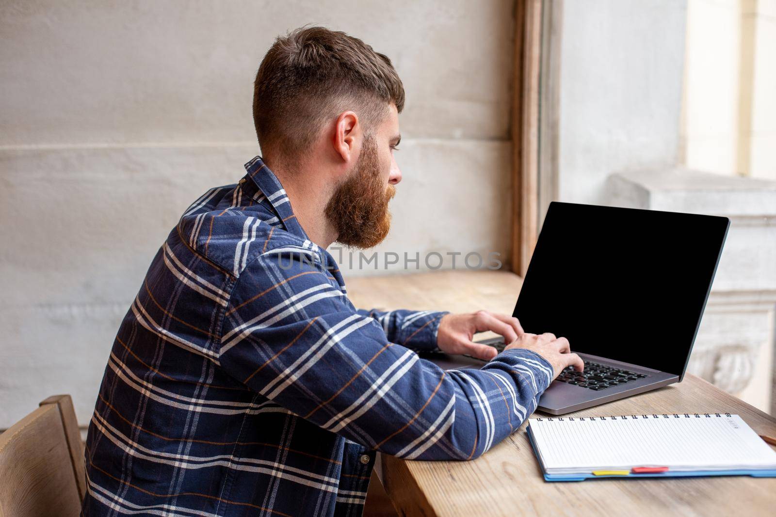 Young man chatting via net-book during work break in coffee shop, male sitting in front open laptop computer with blank copy space screen for your text message or advertising content