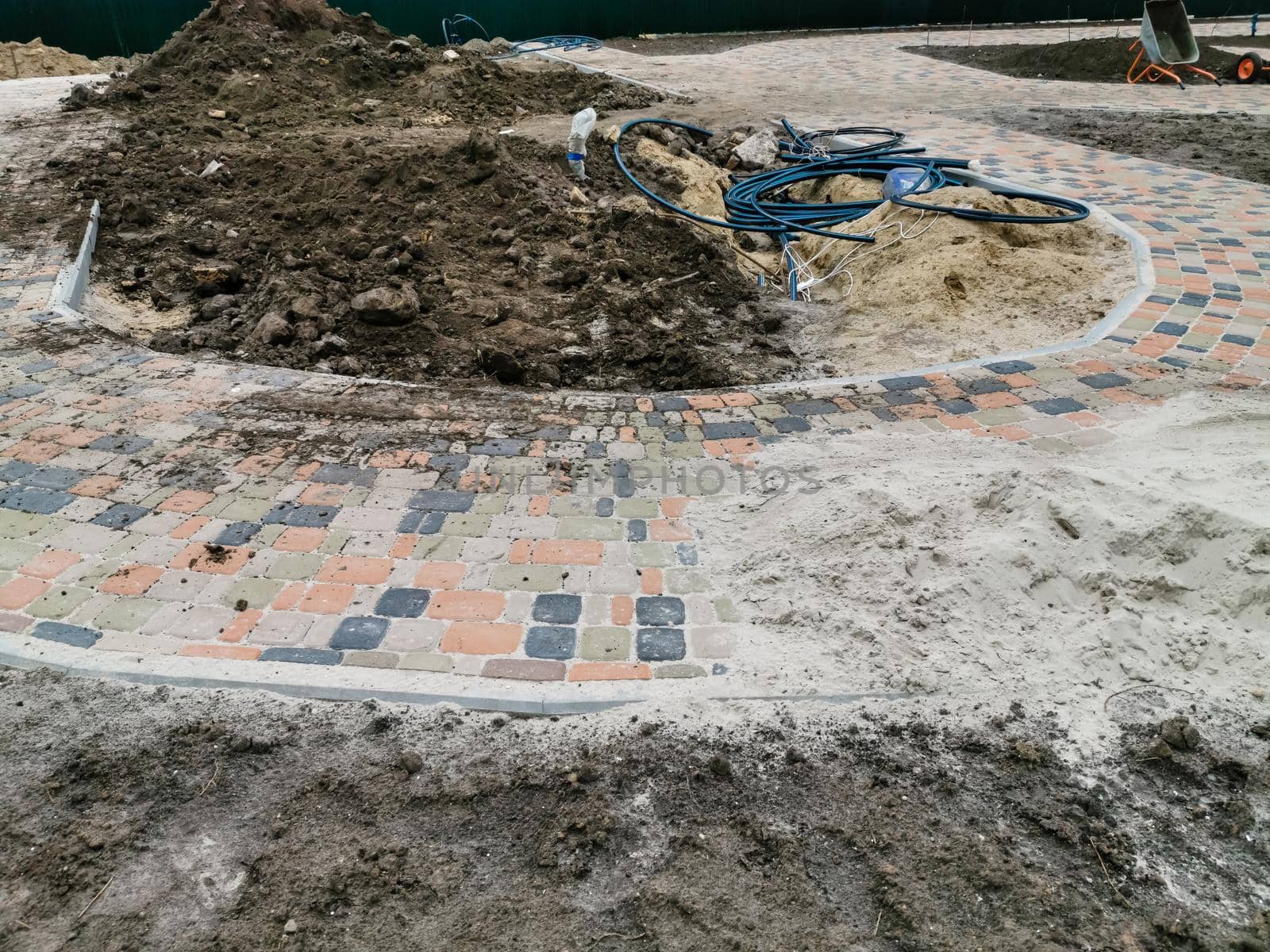 industrial worker installing pavement rocks, cobblestone blocks on road pavement