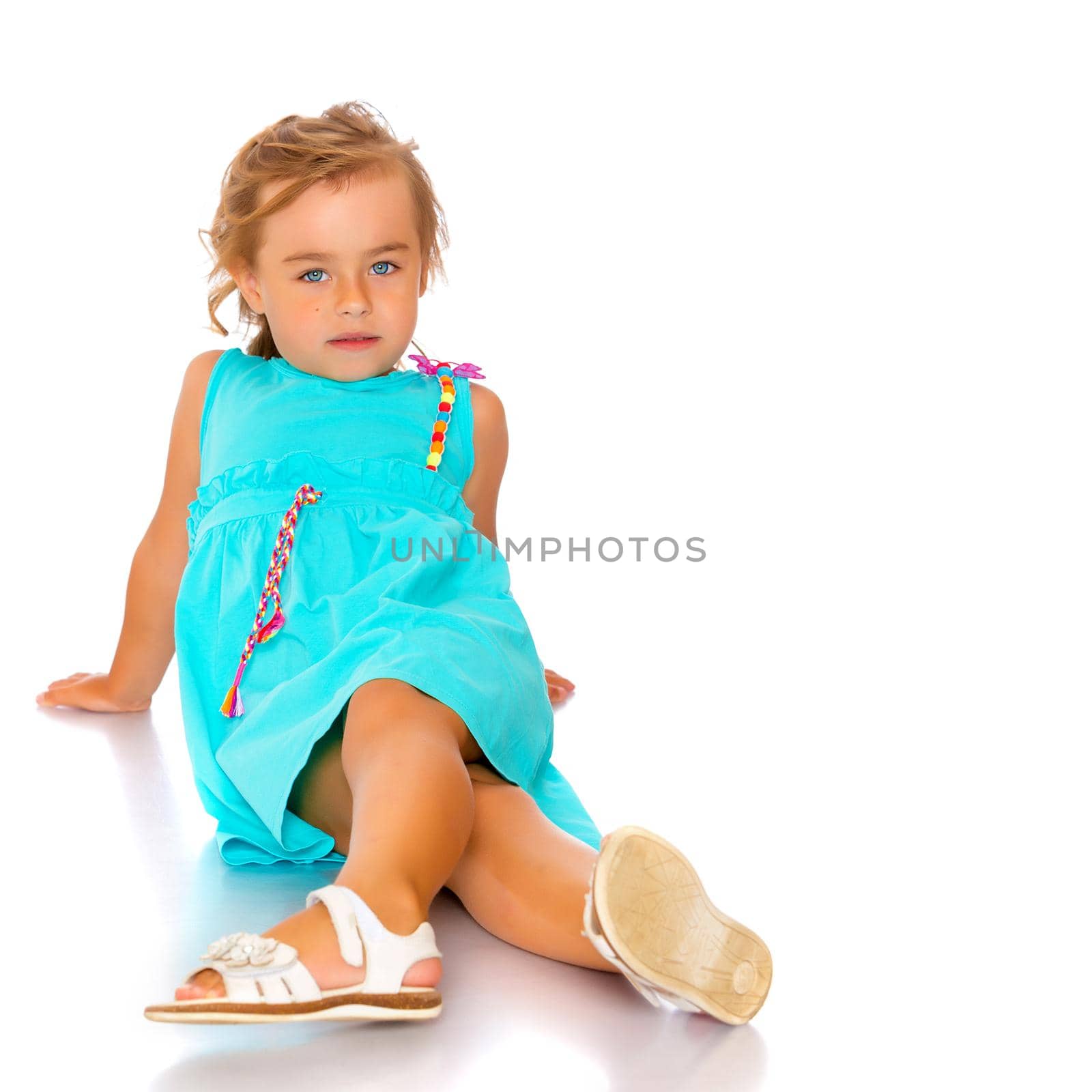 Beautiful little girl lies on the floor on a white background. The concept of a happy childhood, well-being in the family. Isolated.