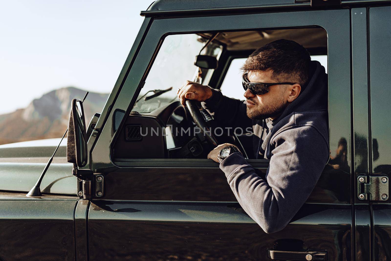 Male driver of an off-road car looking through the window by Fabrikasimf