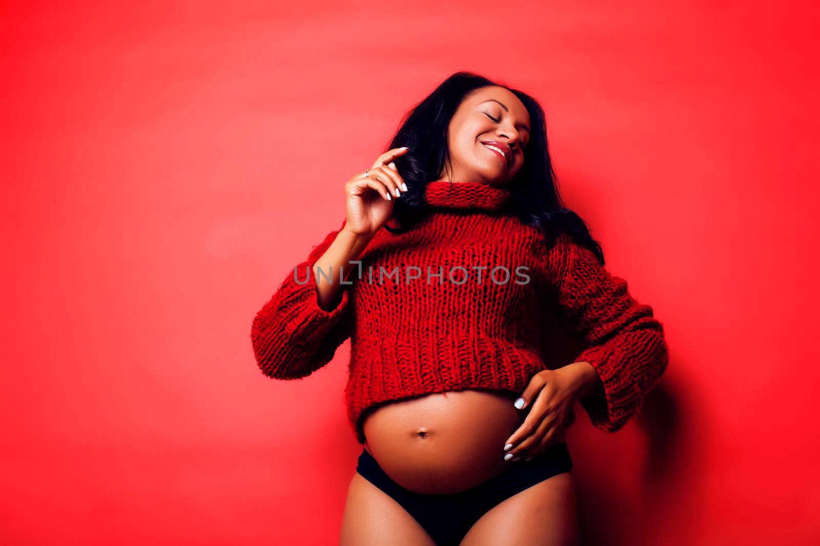 close up portrait of pregnant woman with big belly, hands hold, red sweater on background, choise of gender, lifestyle people concept