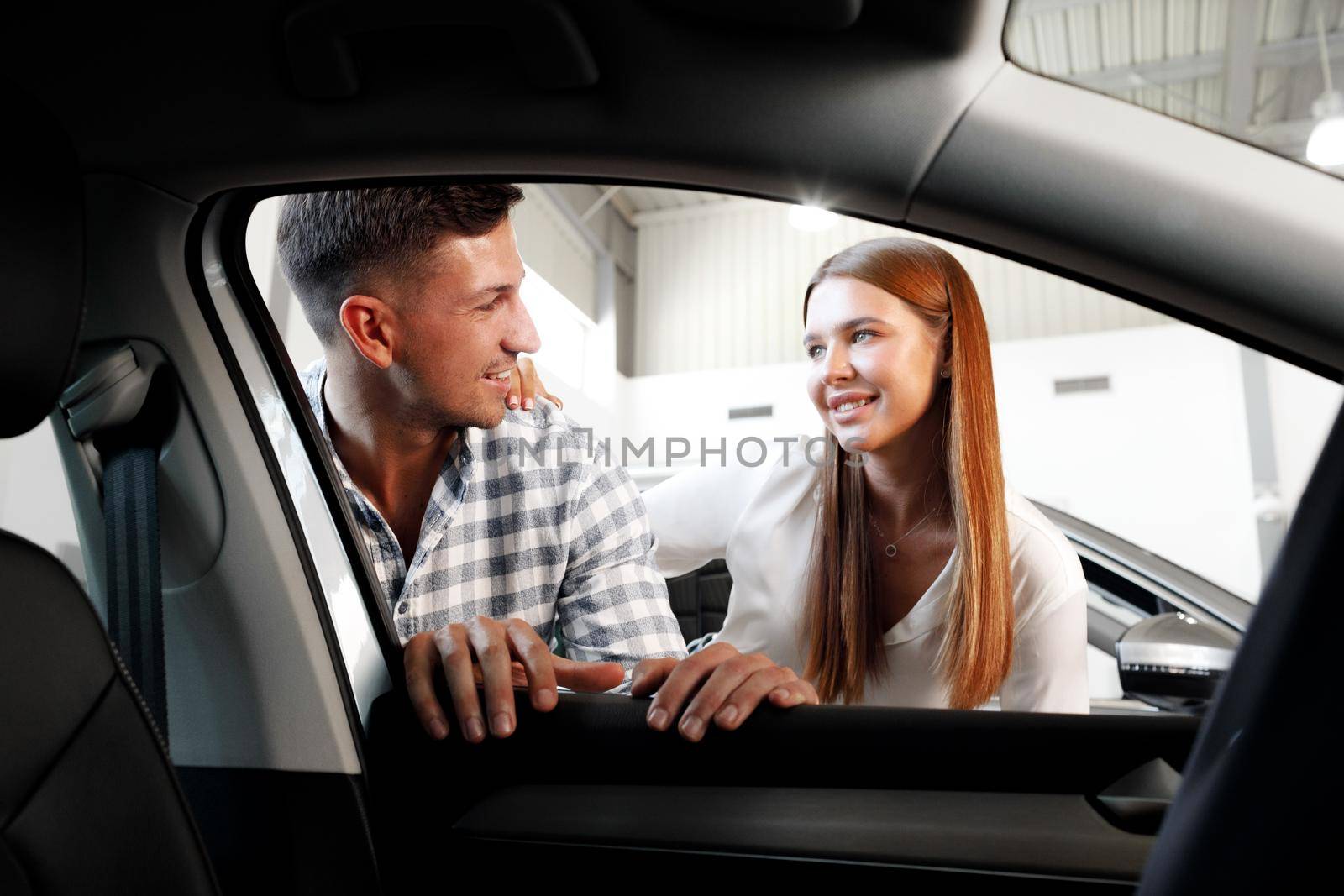 Young couple choosing their new car in a car shop together