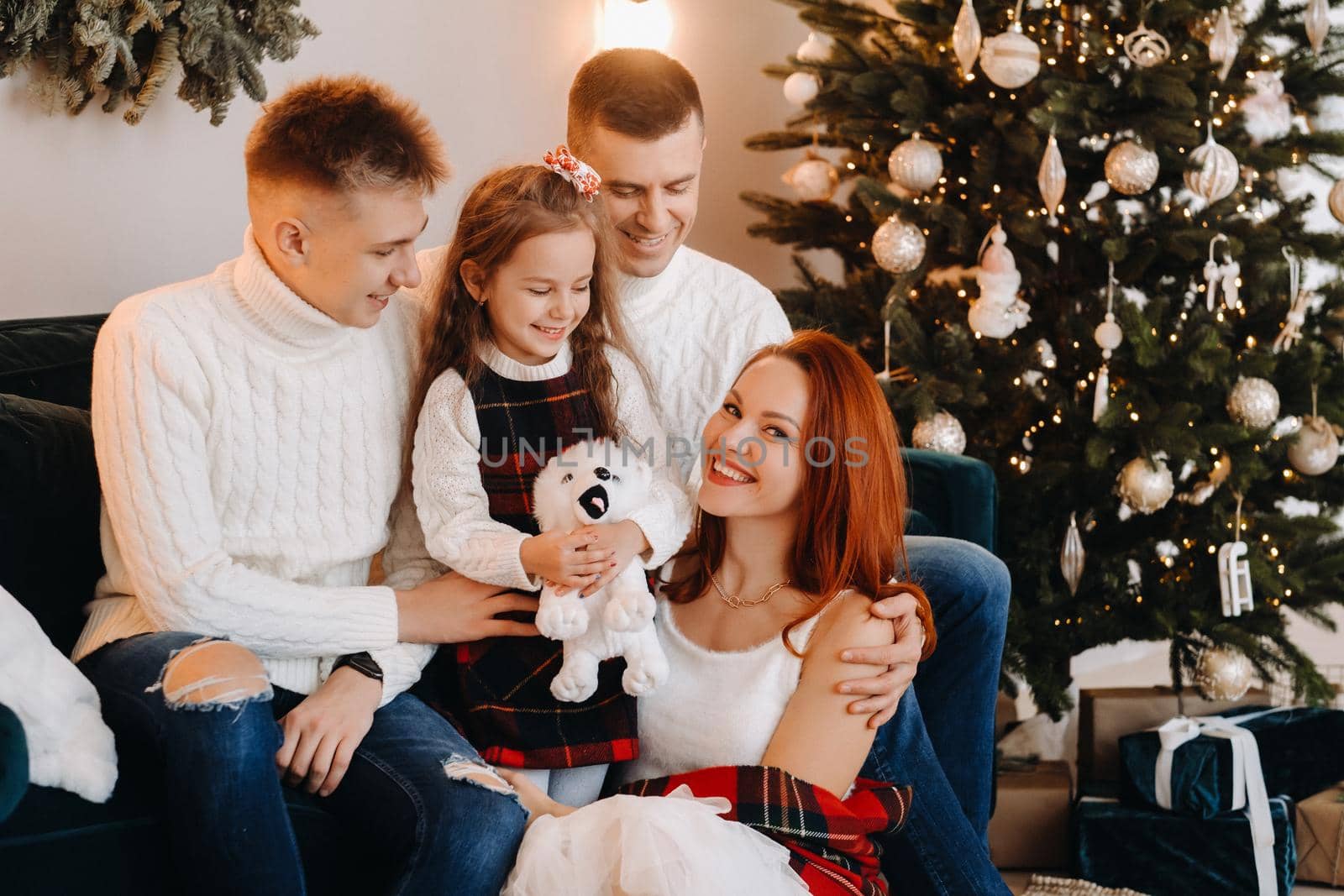 Close-up portrait of a happy family sitting on a sofa near a Christmas tree celebrating a holiday.