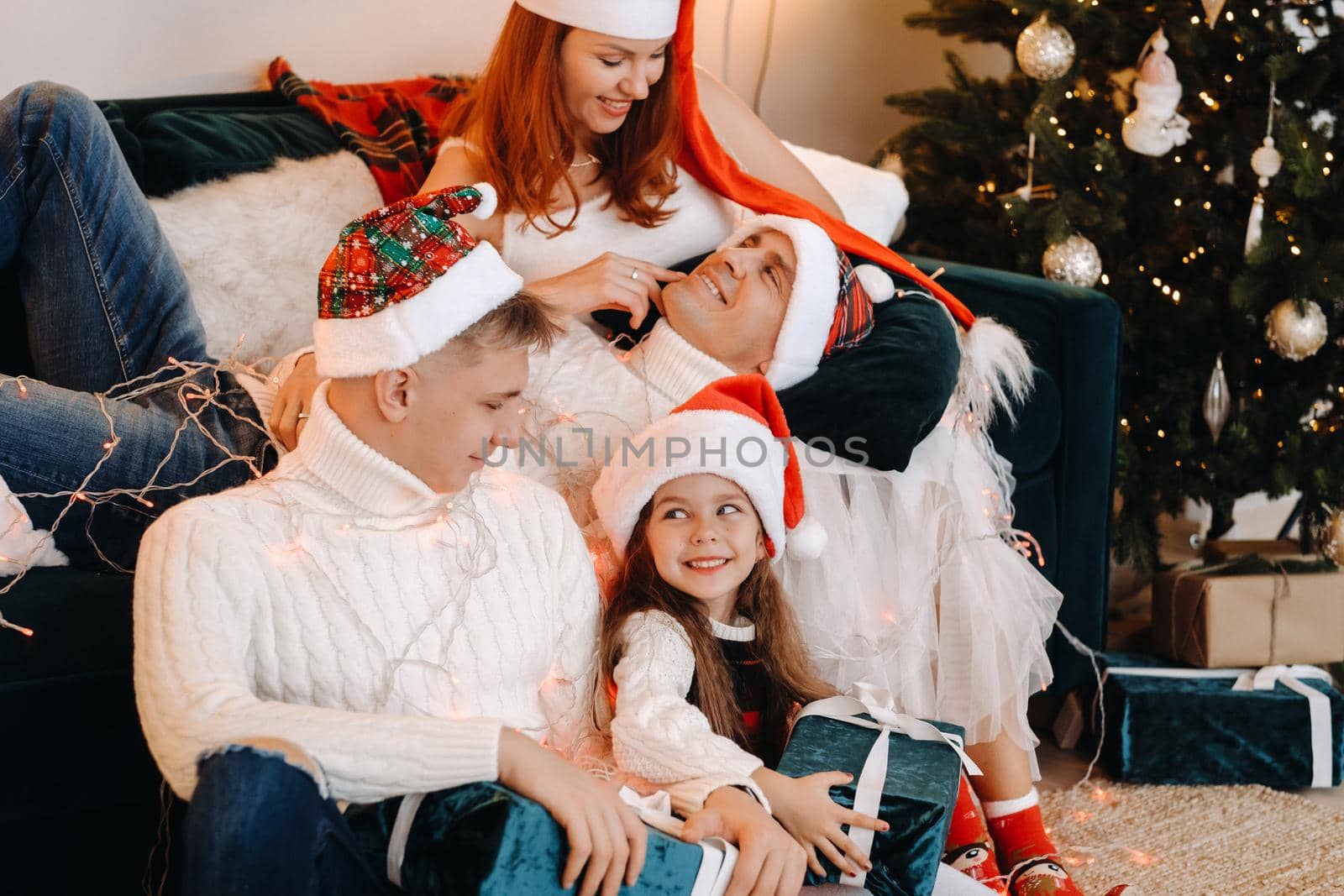 Close-up portrait of a happy family sitting on a sofa near a Christmas tree celebrating a holiday.